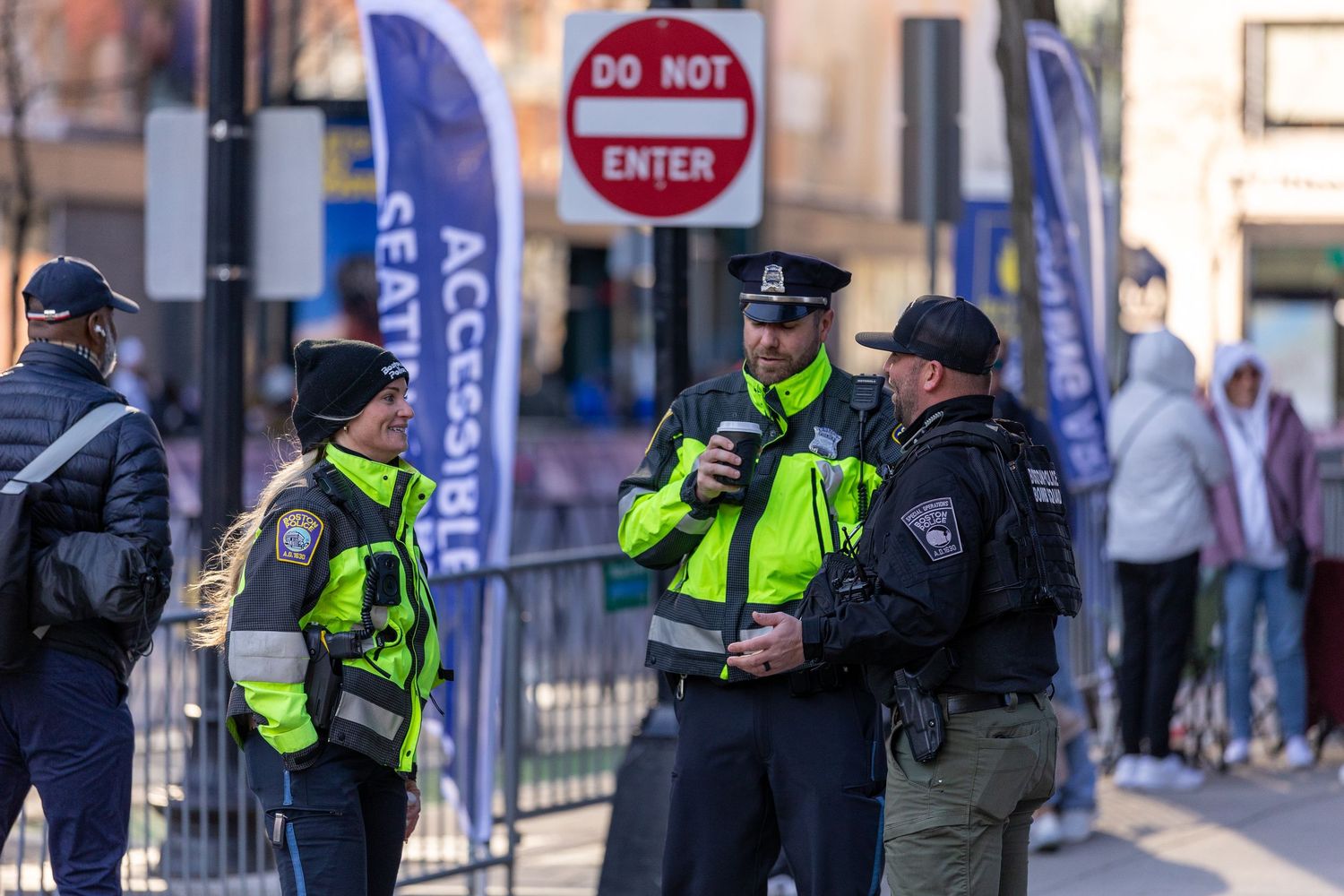 Police officers in high-visibility jackets gather near a Do Not Enter sign at a public event in Boston.