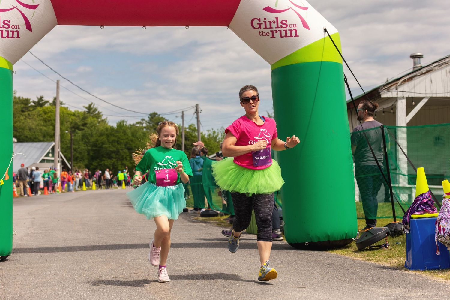 Two females in tutus crossing finish line at Girls on the Run race event.