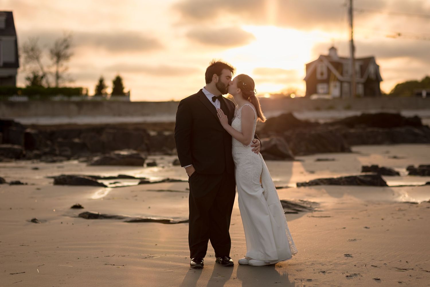 A couple in wedding attire dances romantically on Mother's Beach in Kennebunk, Maine at sunset.