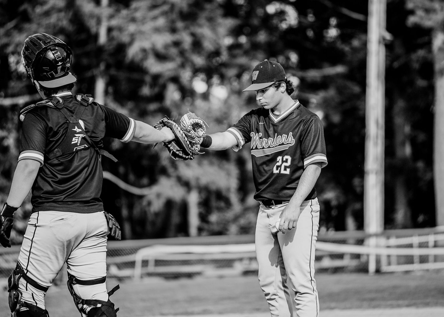 Two baseball players fist bumping on the field in black and white, wearing uniforms with numbers 22.
