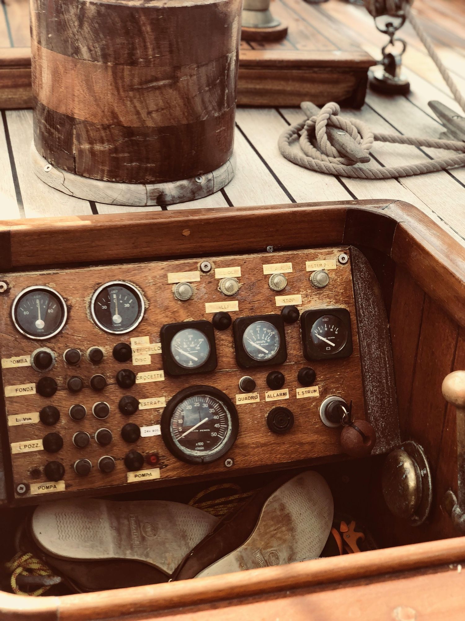 Vintage wooden control panel with brass gauges and switches mounted in rich mahogany wood on a rustic table.