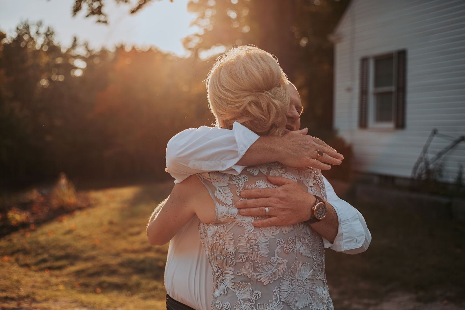 Emotional embrace captured during golden hour outside rustic farmhouse.