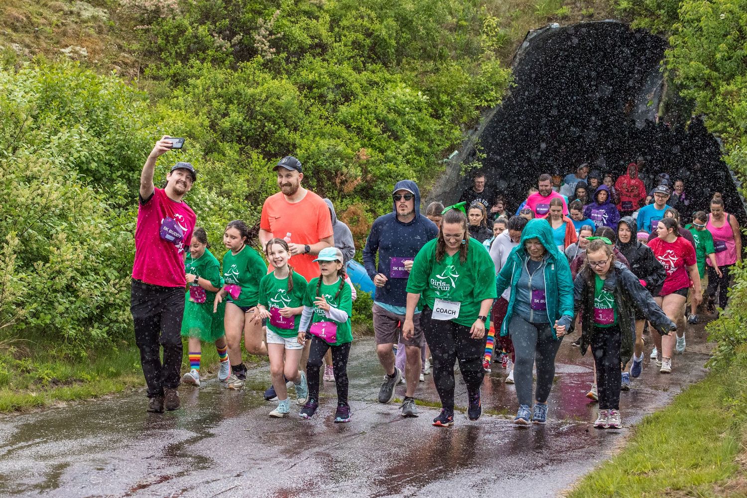 Large group of runners in colorful shirts participating in a charity fun run on a rainy day outdoors.