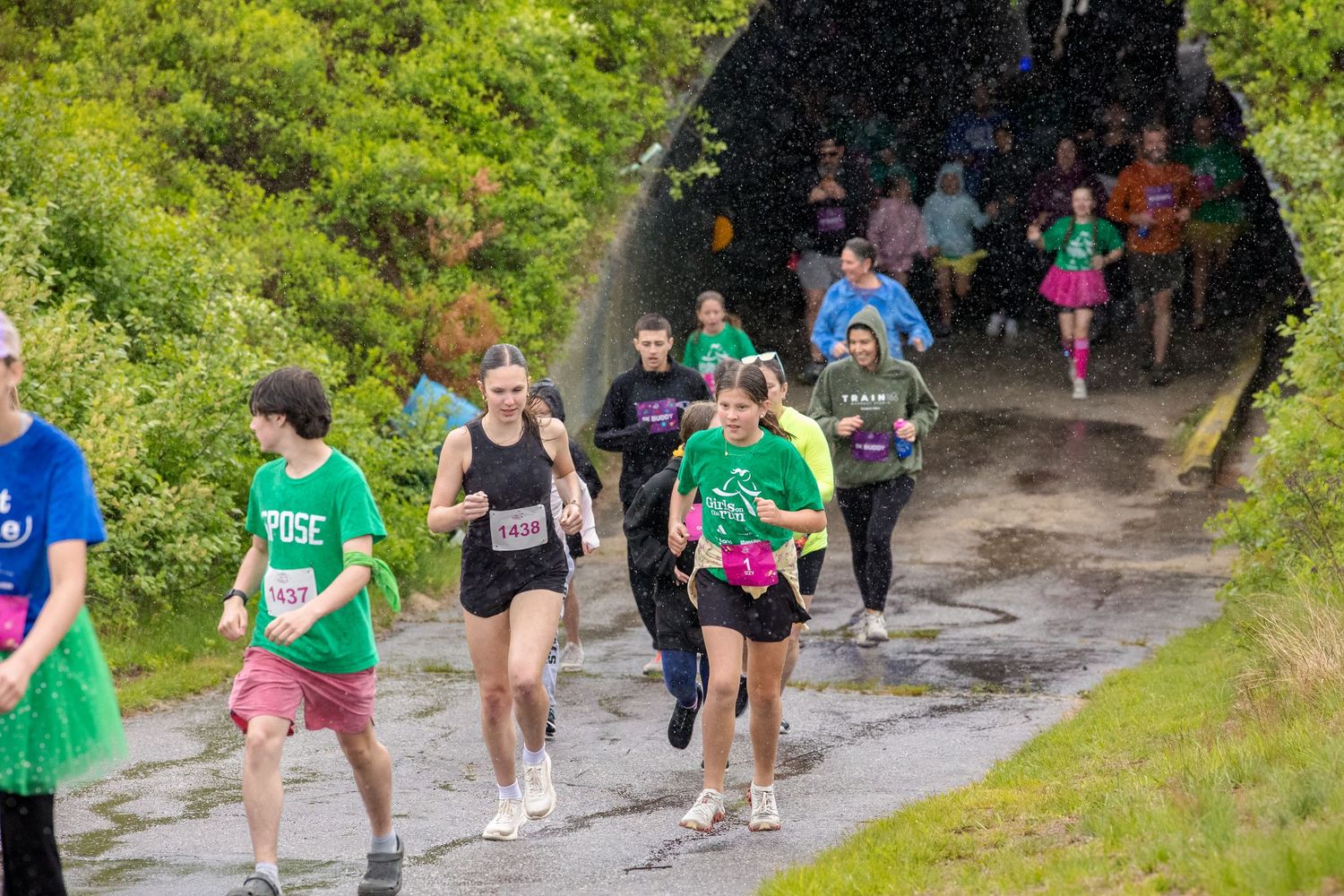 Runners in colorful outfits race along a scenic trail path during an outdoor charity fun run event.