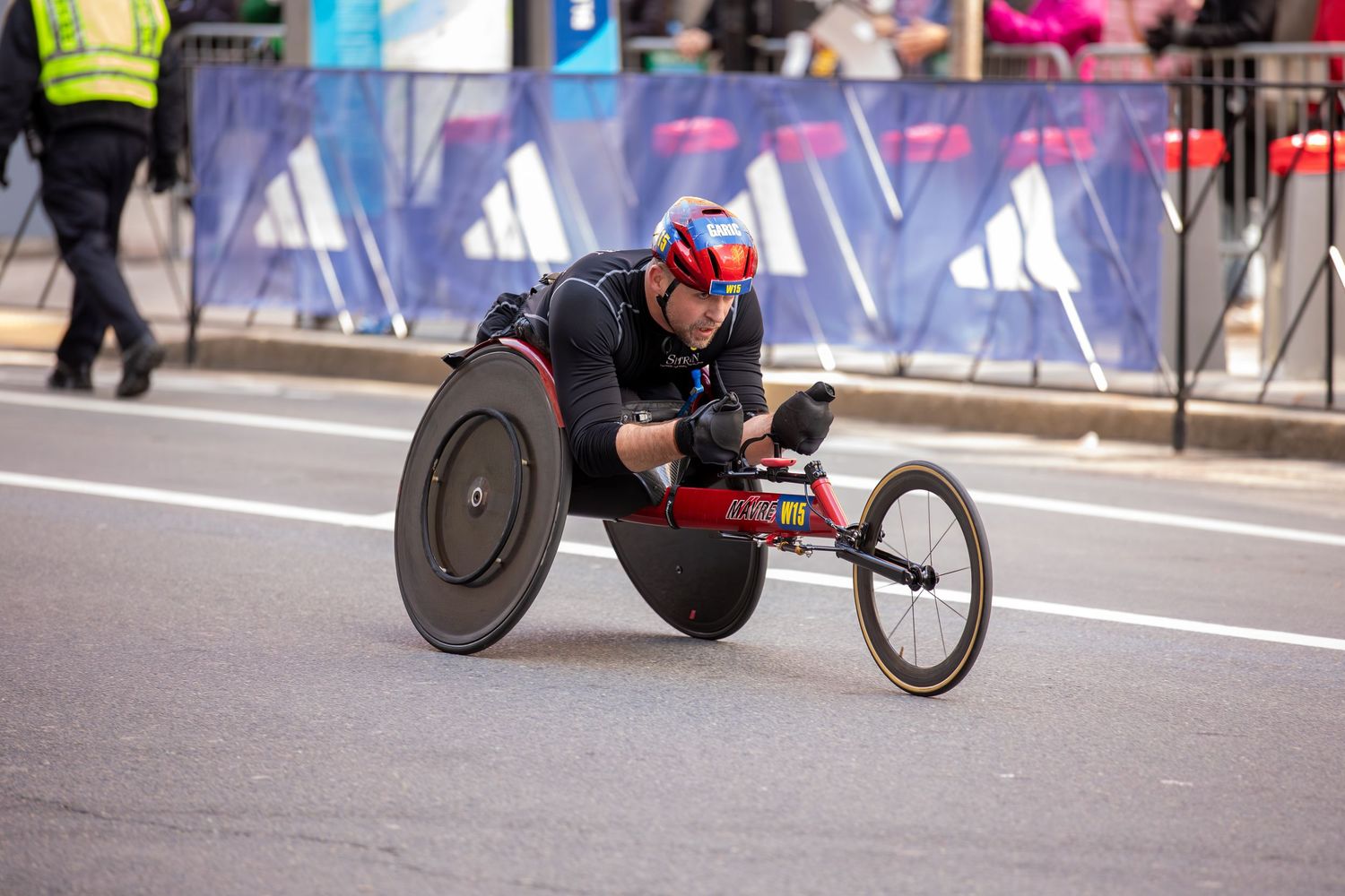 Athlete competing in a wheelchair racing event on a city street during a marathon race.