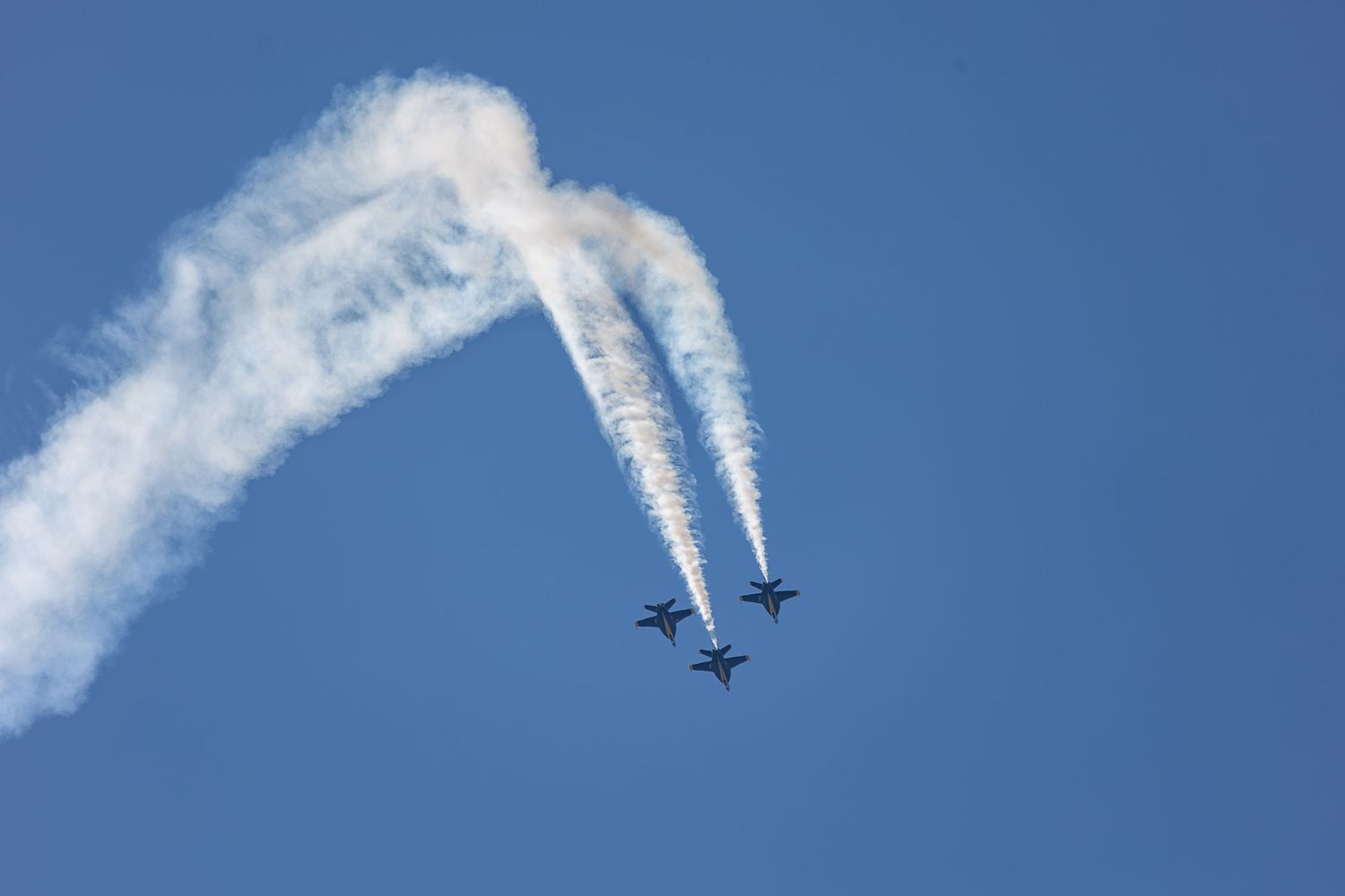 A sequence of images showing a passenger jet flying through blue skies leaving white contrails behind.