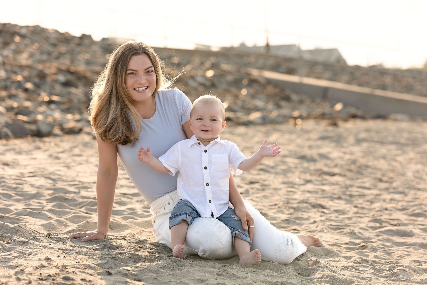 Family playing together on sandy beach during golden hour sunset.