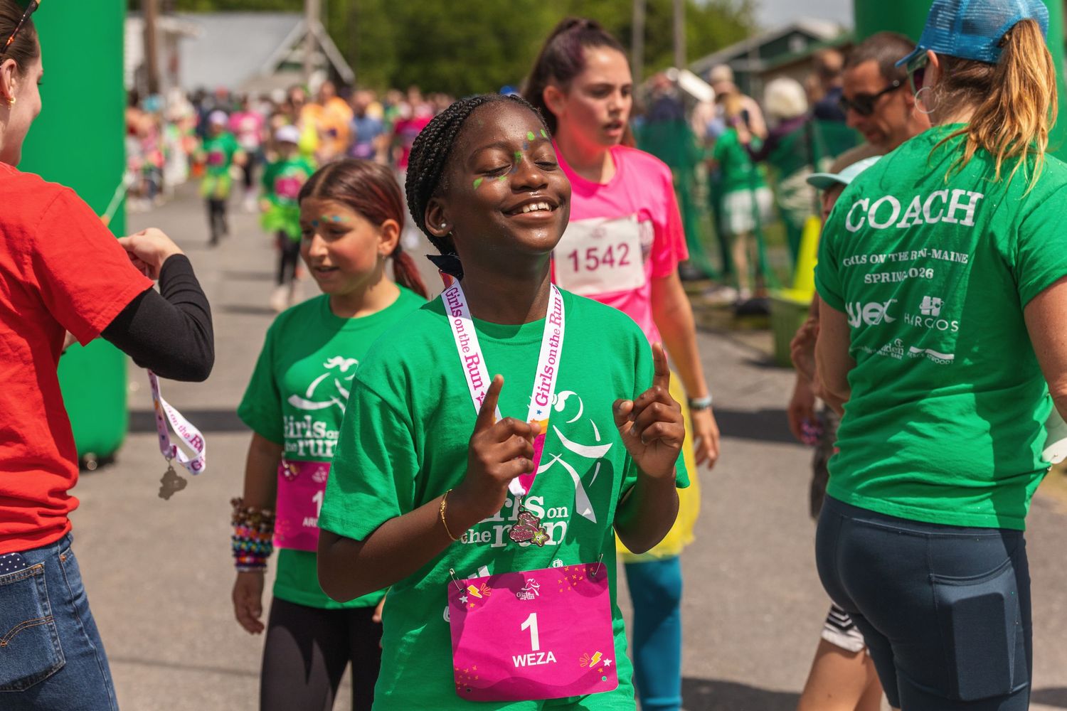 Young girl wearing medal celebrating at Girls on the Run 5K race event.