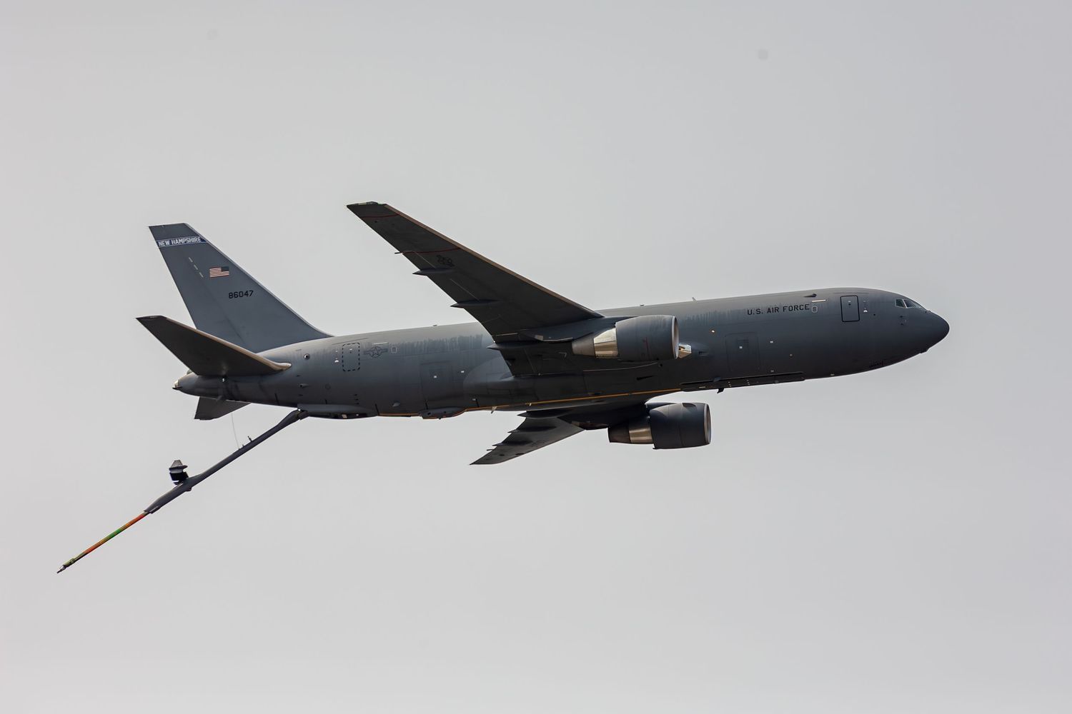 Military aircraft performing aerial refueling maneuver with fuel boom extended between two planes in flight.