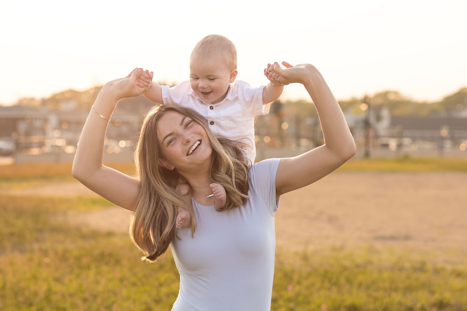Family enjoying playful moment in golden sunlit field during sunset.