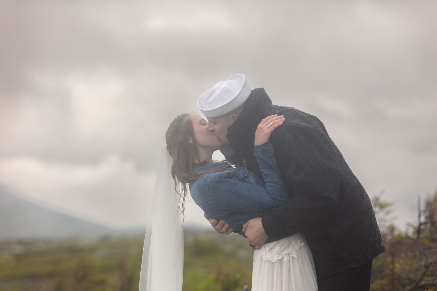 A couple shares a romantic kiss in front of scenic mount Washington mountain during their outdoor elopement wedding ceremony.