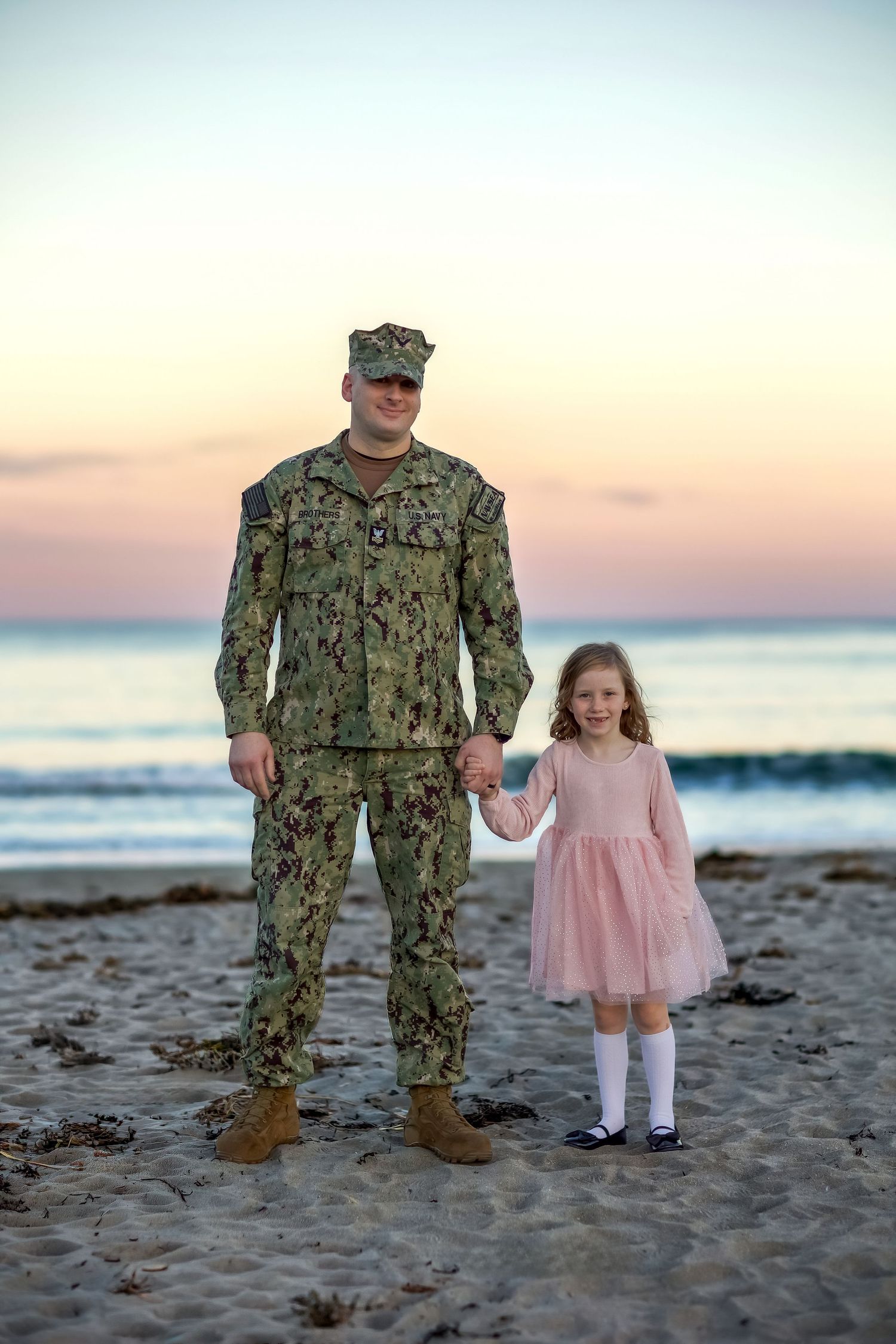 A series of beach photos showing a person in military uniform standing with a small child in a pink dress at sunset.