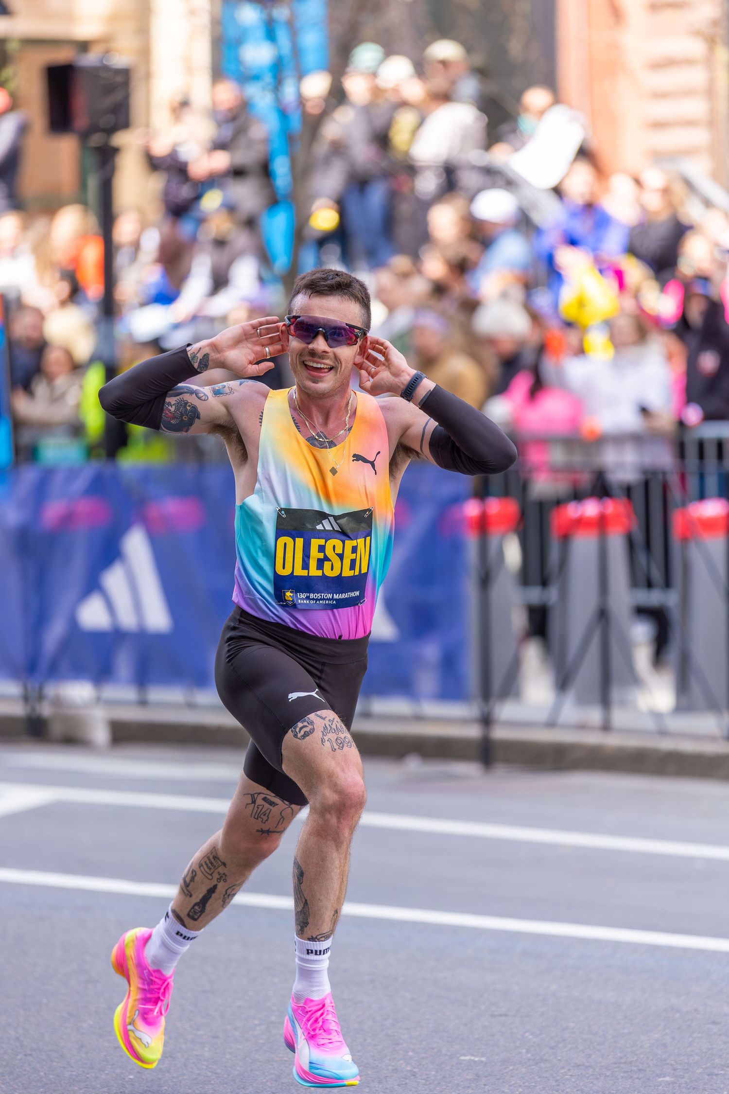 Runner Olesen wearing colorful Adidas vest and pink shoes competing in a city marathon race.