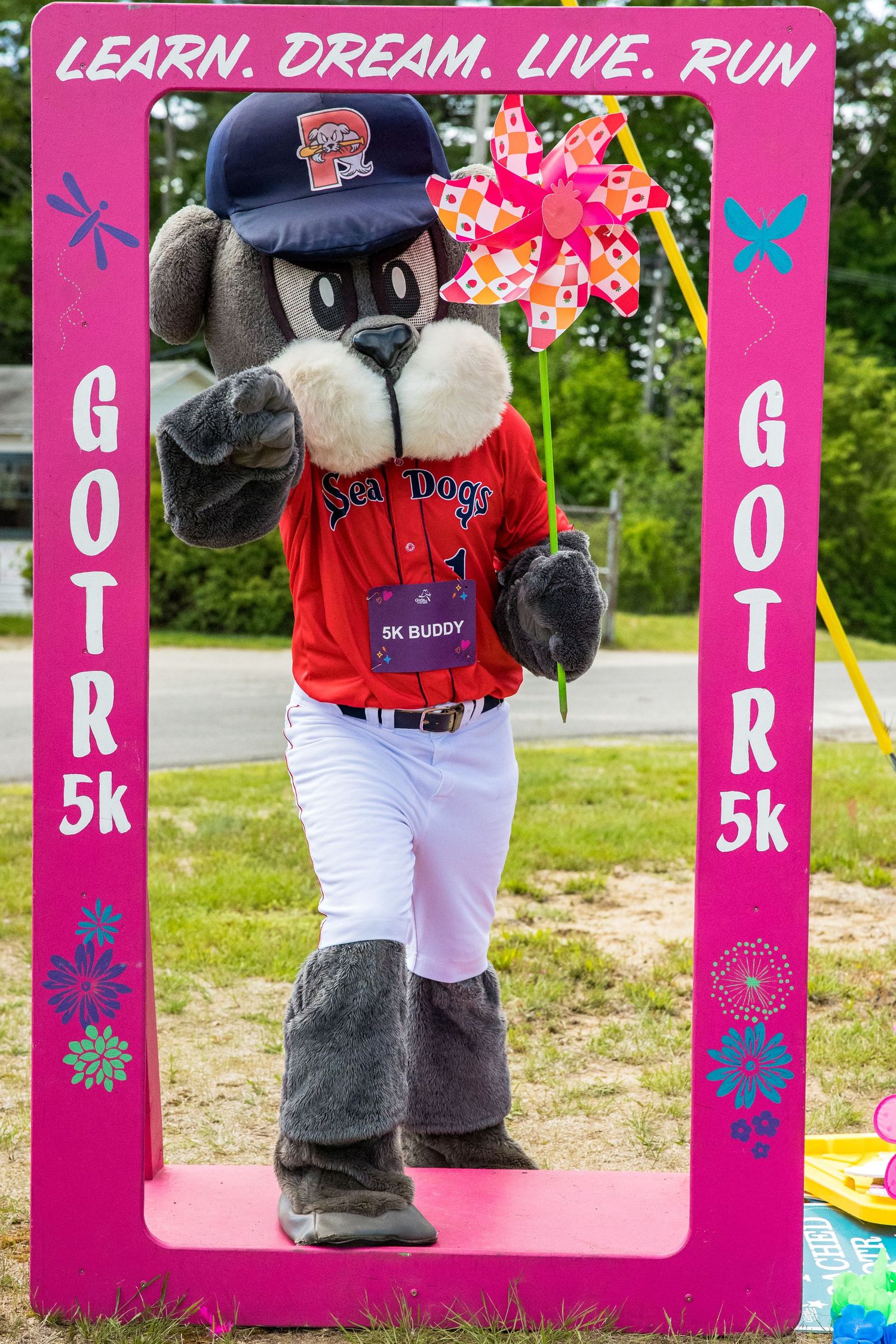 Sea Dogs mascot 5K Buddy poses in a GOTR 5k photo frame at a Girls on the Run event.
