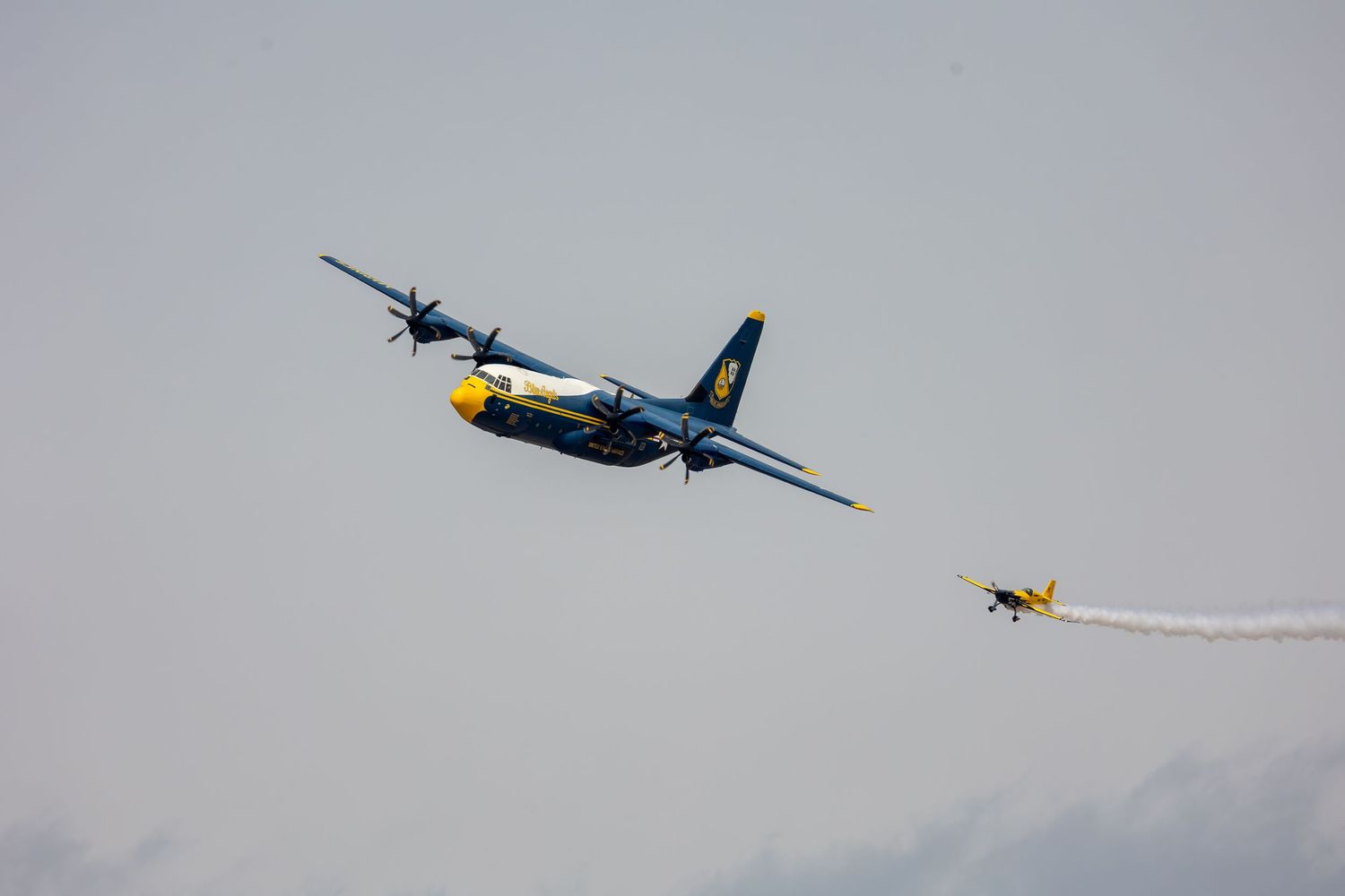 A vintage World War II fighter plane performs an aerial maneuver against a cloudy sky background.