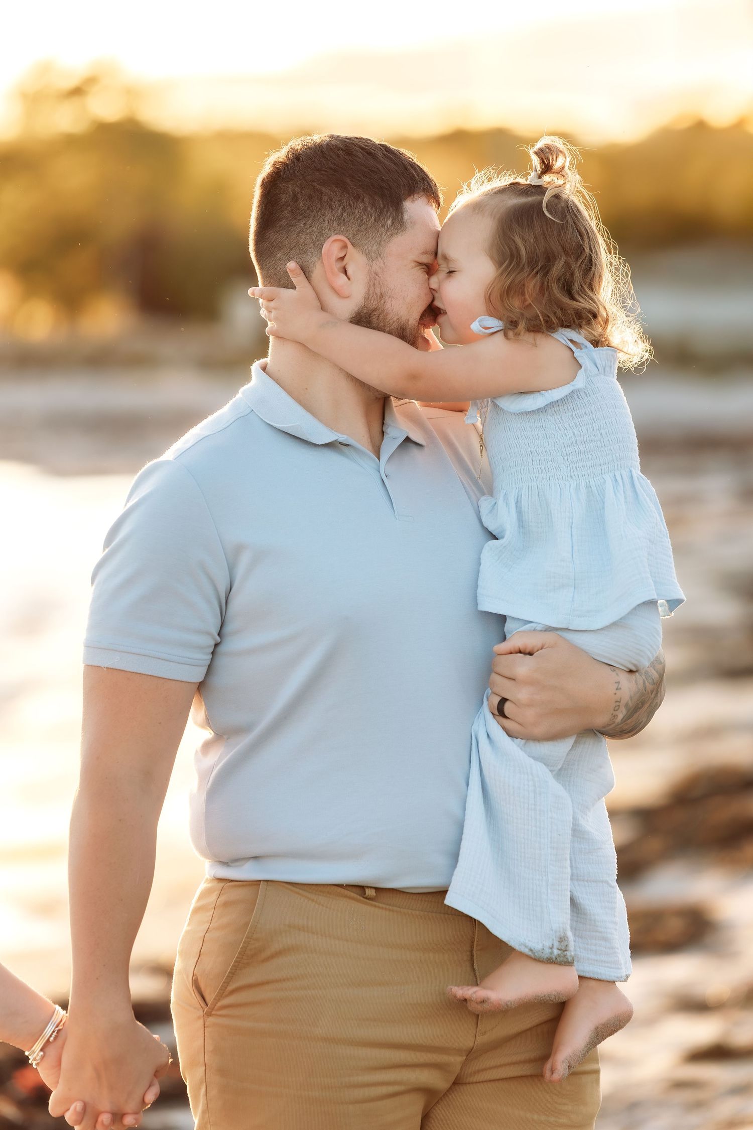 A touching moment captured between two people during golden hour on a rocky beach.