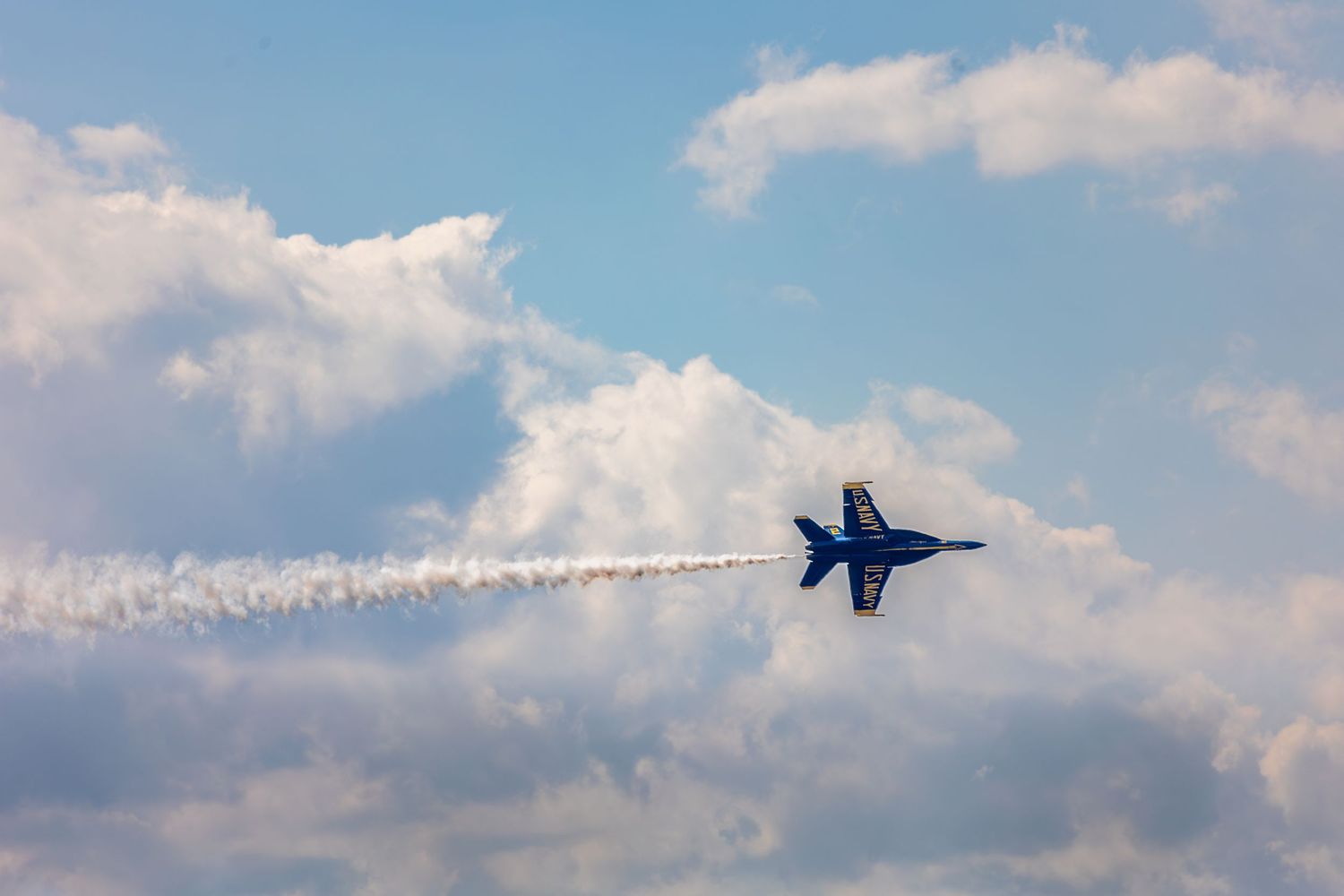 A sequence of photos showing a Blue Angels F/A-18 Hornet jet performing aerial maneuvers against a blue sky with clouds.