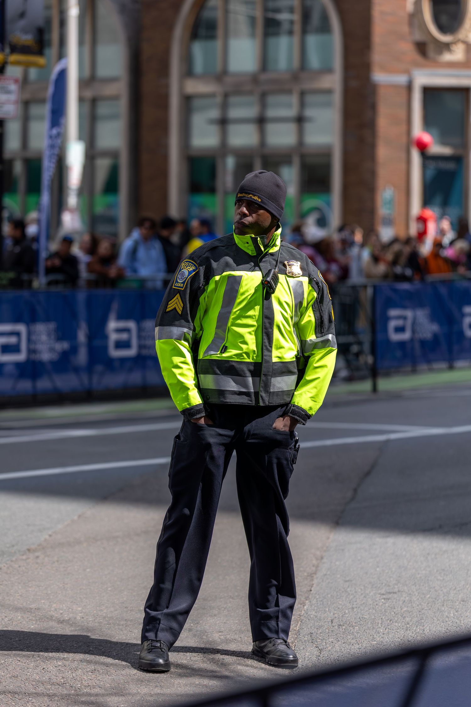Security officer in high-visibility yellow jacket standing on street during outdoor public event.