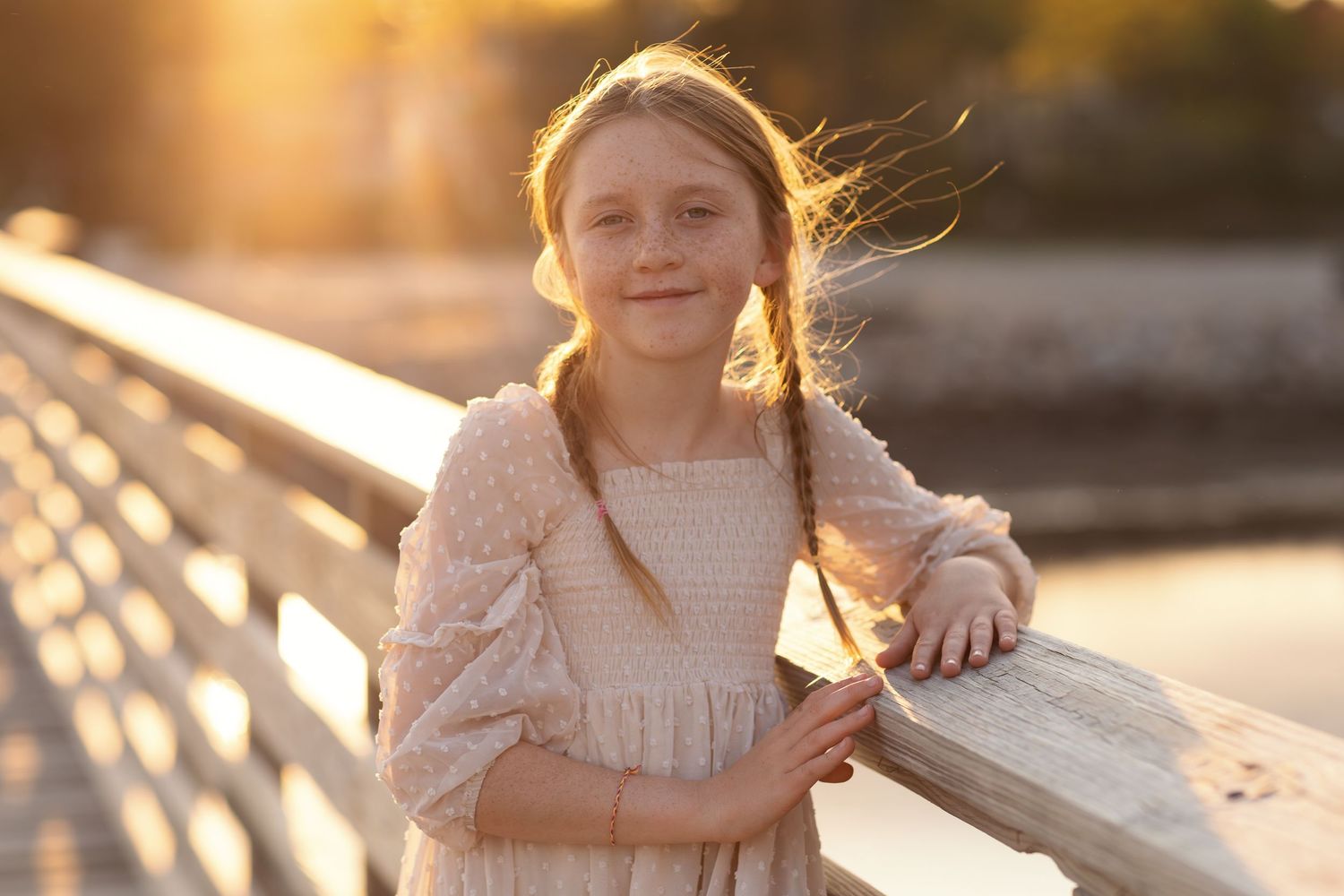 Siblings share tender moments together on a boardwalk during golden hour.