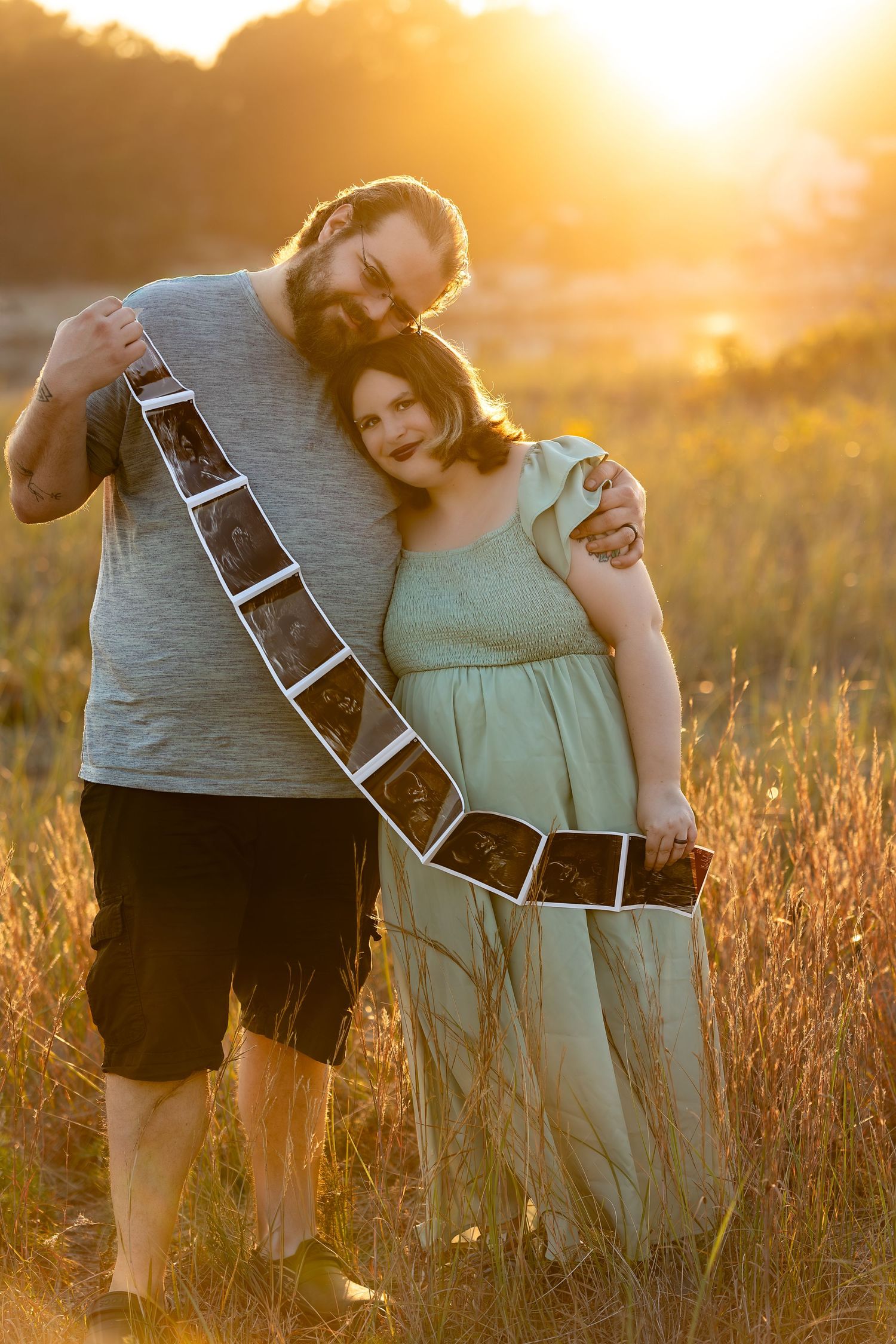 A couple embraces in a golden wheat field at sunset creating a romantic silhouette against the warm glowing sky.