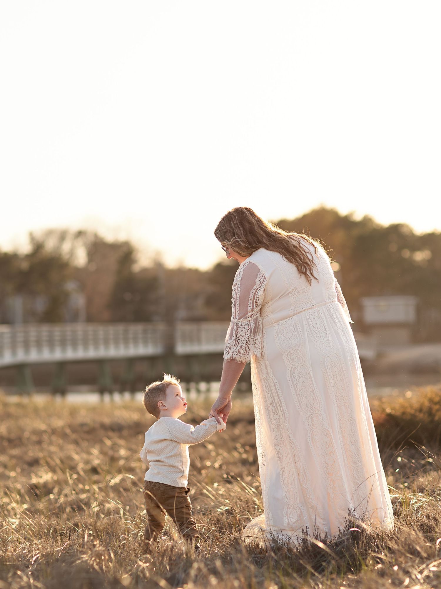 A parent and child share a sweet moment in a golden field at sunset.