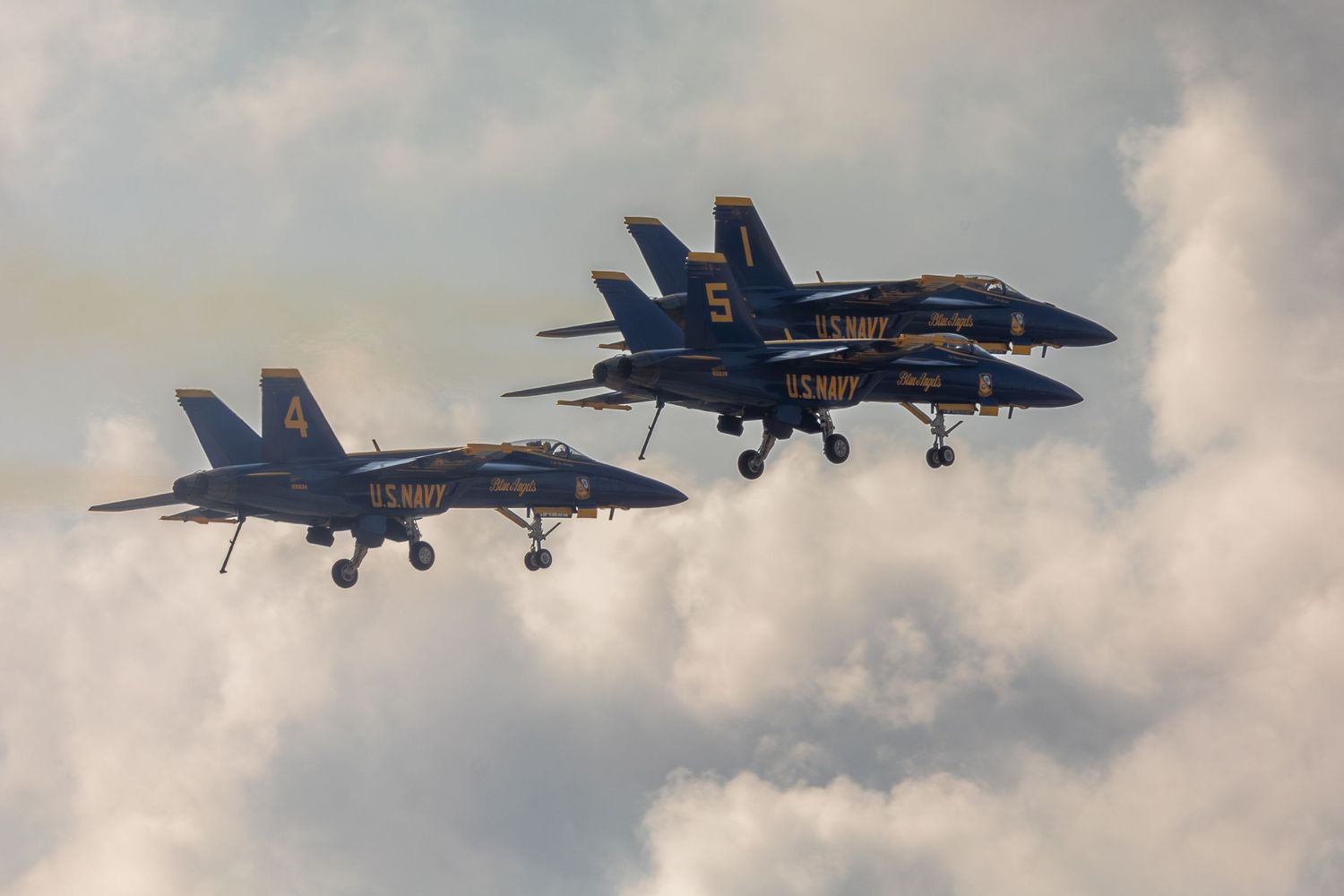 A sequence of US Navy Blue Angels F/A-18 Hornet fighter jets performing aerial maneuvers against a cloudy sky.
