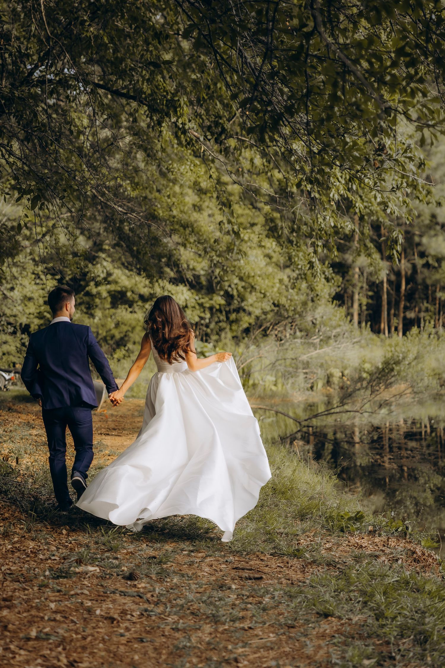 Bride and groom walking through a lush green forest in Georgia, candid elopement photography in a forest setting by Julia Tris.