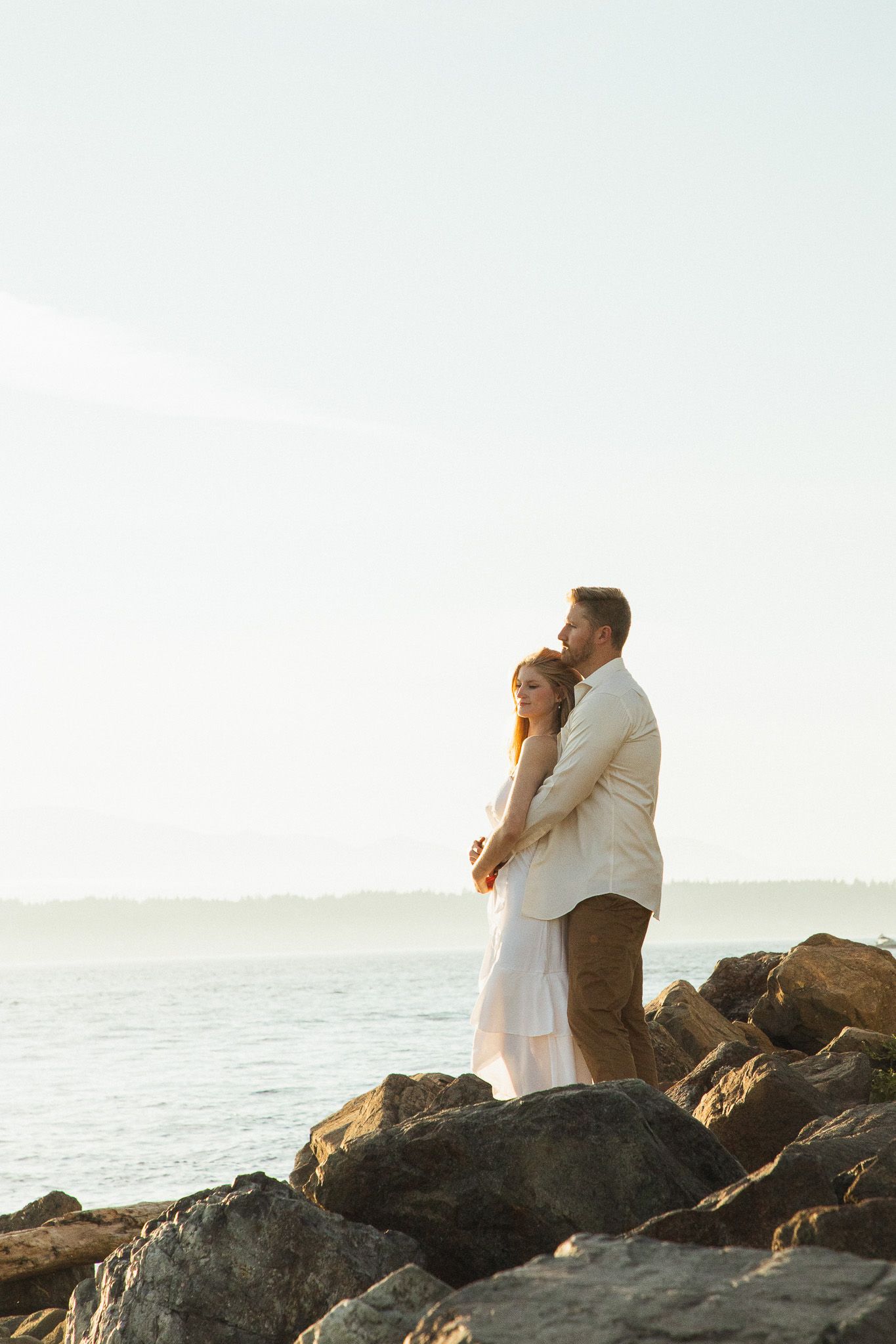 Seattle couples photographer capturing a golden hour couple photoshoot at Discovery Park with Puget Sound views in the background