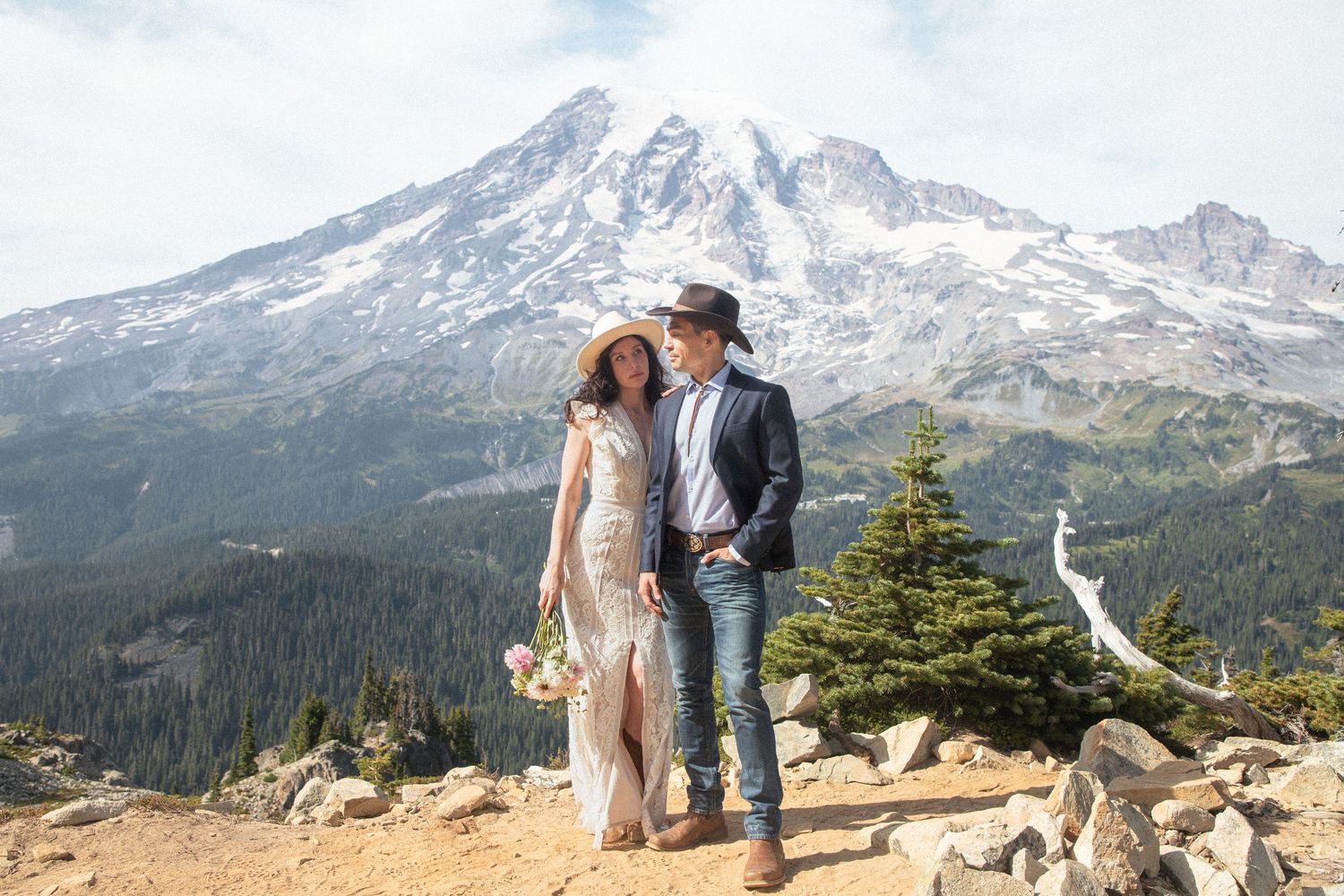Bride and groom together on a mountain overlook with snow-covered Mount Rainier in the background