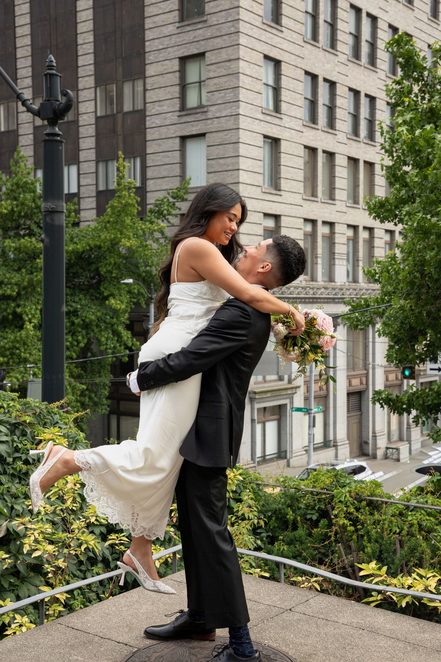Groom lifting the bride during newlywed portraits after their Seattle courthouse wedding ceremony