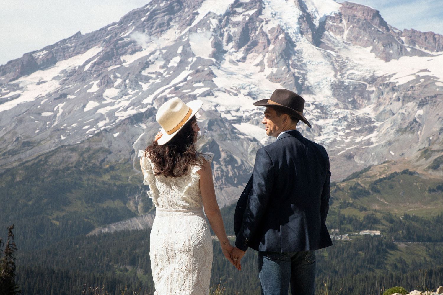 Bride and groom looking at each other while facing Mount Rainier from a scenic overlook