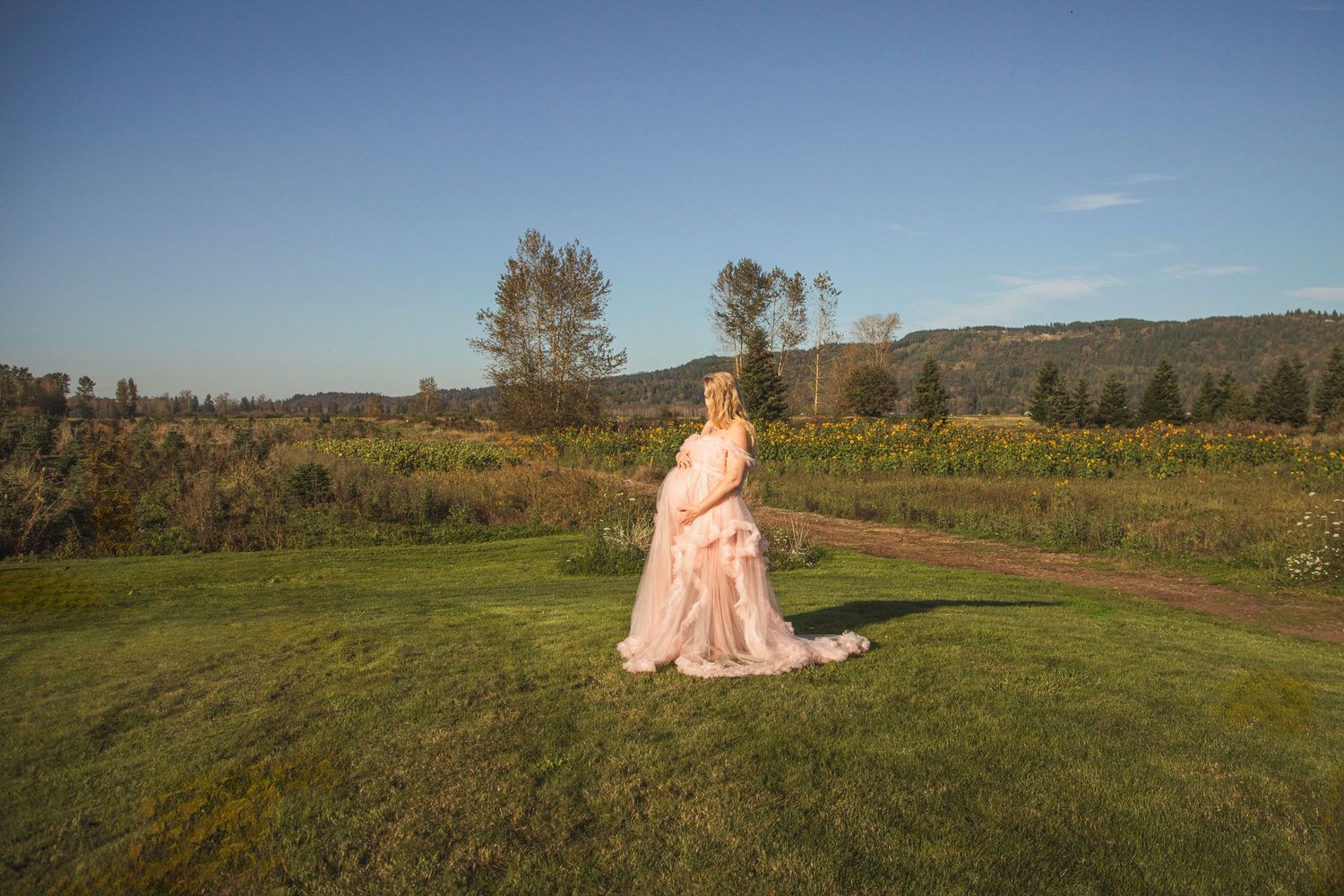Pregnant woman standing alone holding her baby bump, timeless maternity portrait by a Seattle photographer