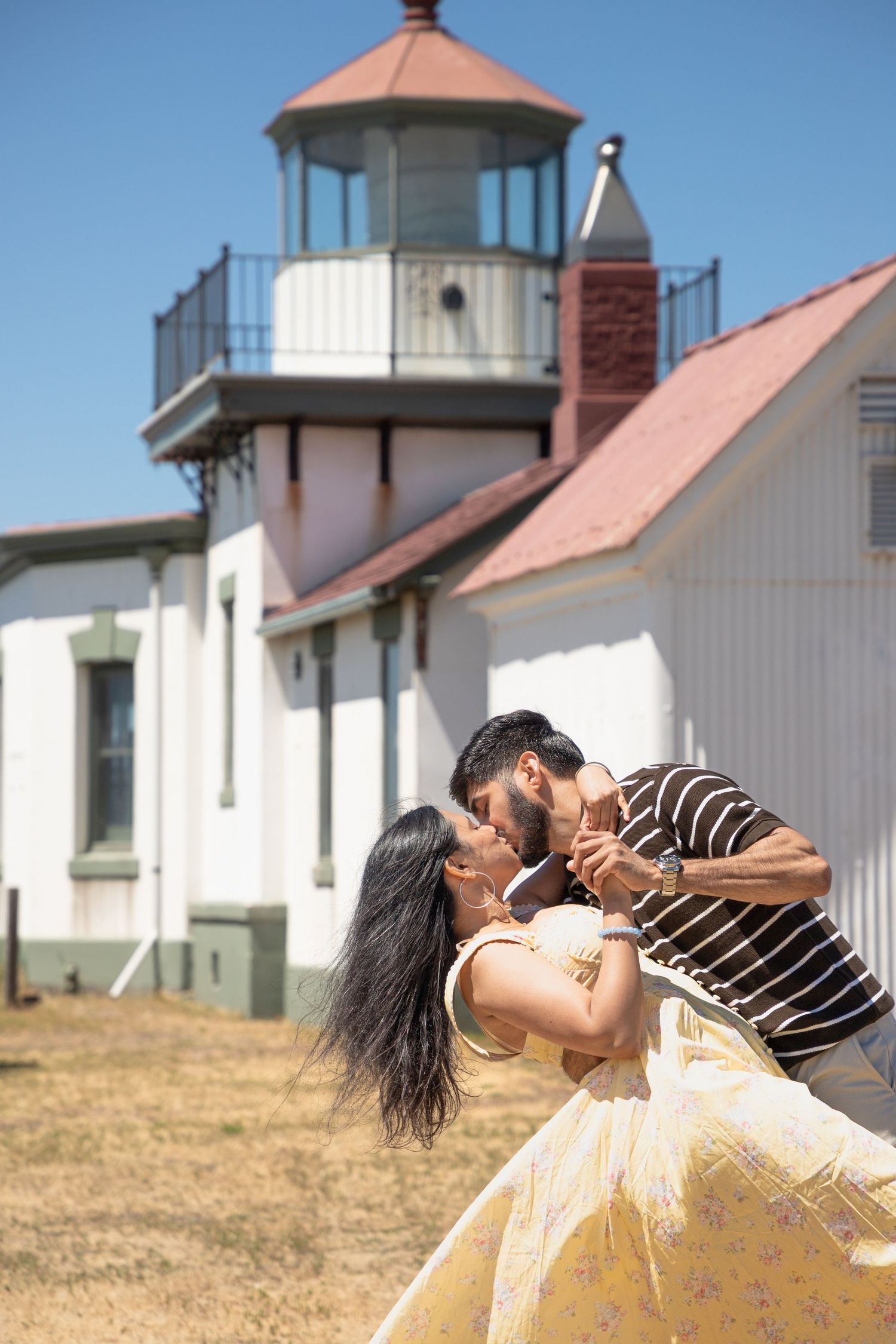 Romantic dip kiss in front of West Point Lighthouse during a Discovery Park engagement photoshoot
