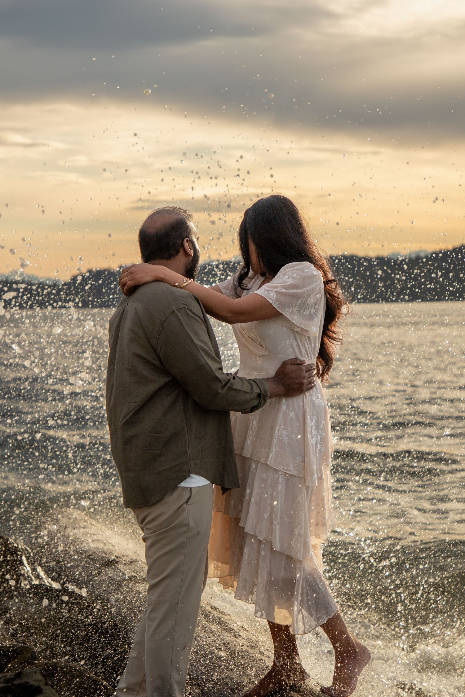 Couple embracing by the water during a sunset proposal photoshoot at Mukilteo Lighthouse Park