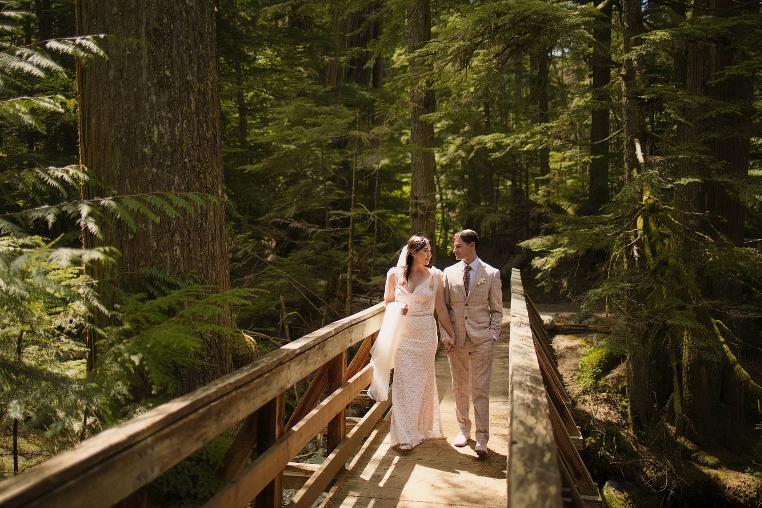 Newlywed couple walking across a forest bridge during an intimate Washington elopement adventure