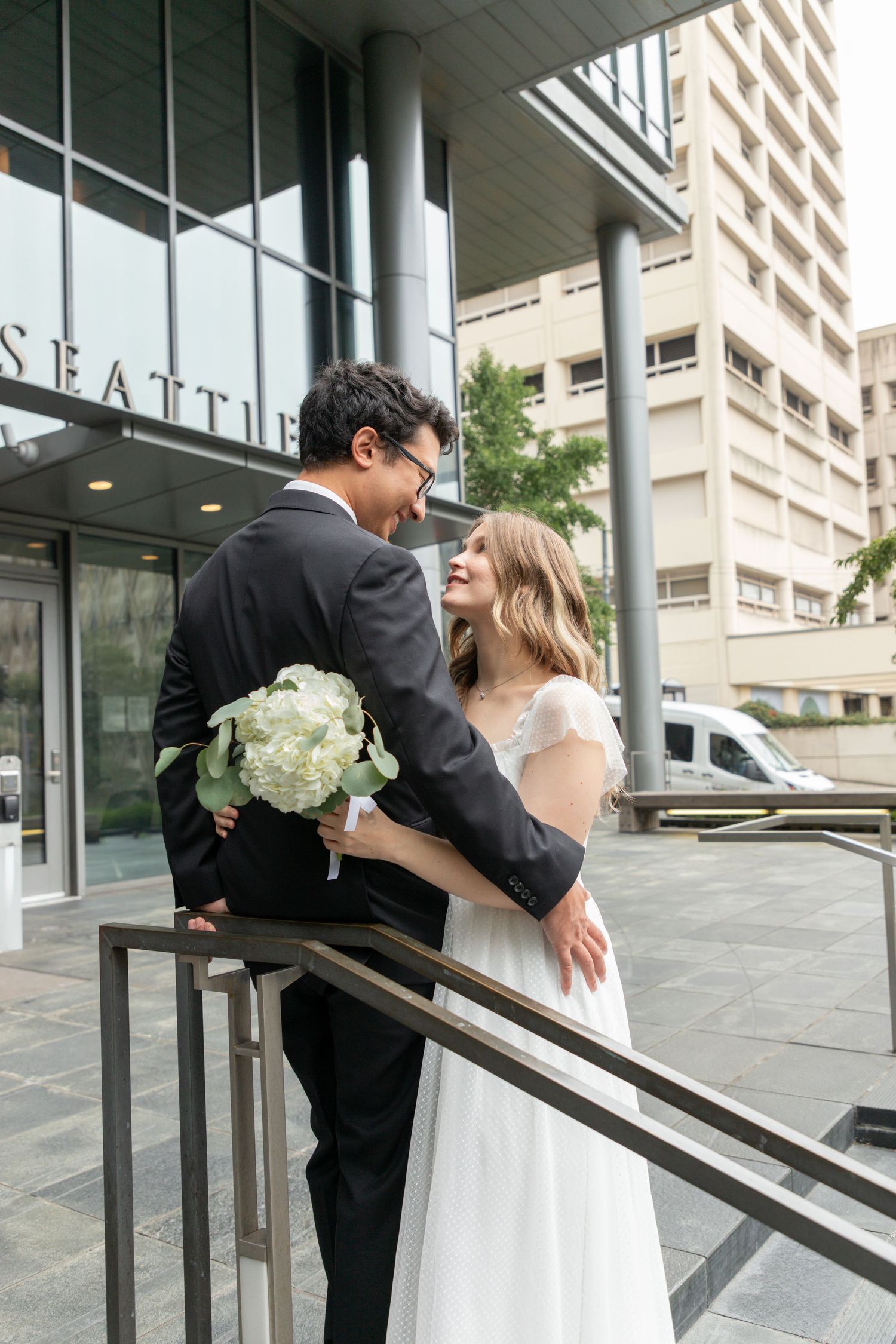 Bride and groom embracing outside the Seattle Justice Center after their courthouse ceremony
