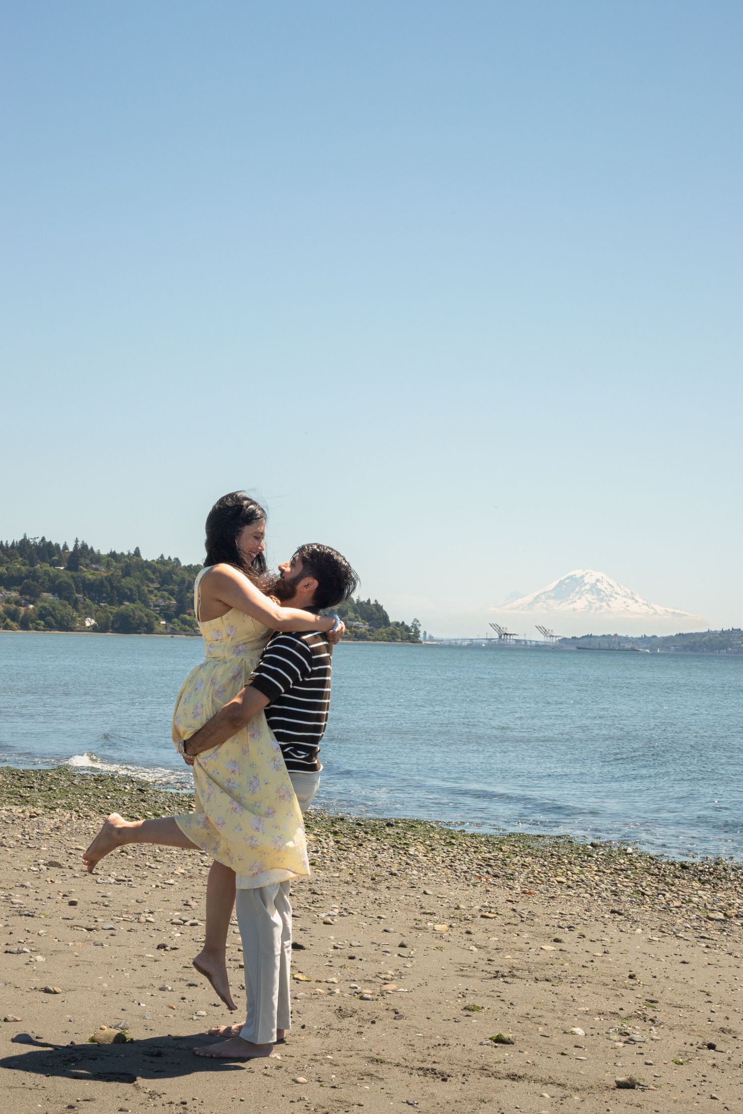 Joyful couple embracing on the beach with Mount Rainier in the background after their Seattle proposal