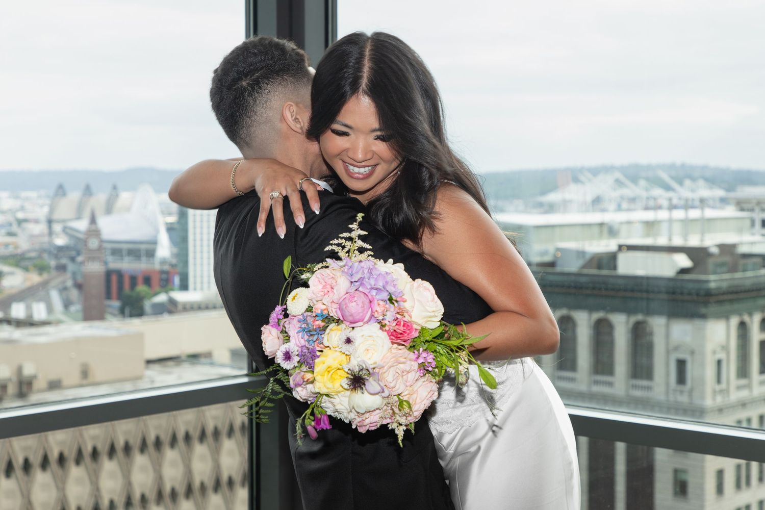 Newlywed couple embracing with a colorful bouquet on the Seattle Municipal Court rooftop