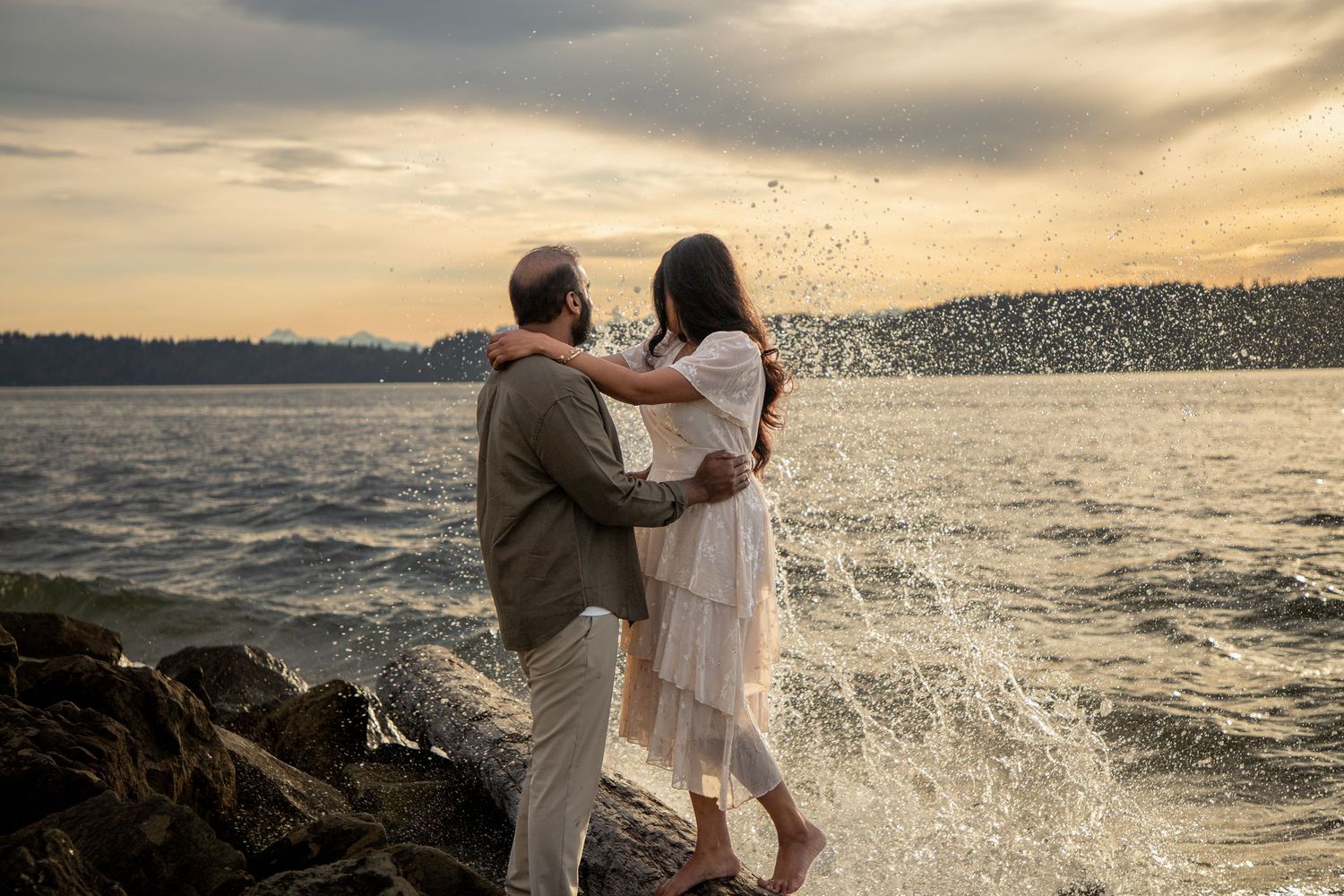 Couple embracing by the water during a sunset proposal photoshoot at Mukilteo Lighthouse Park