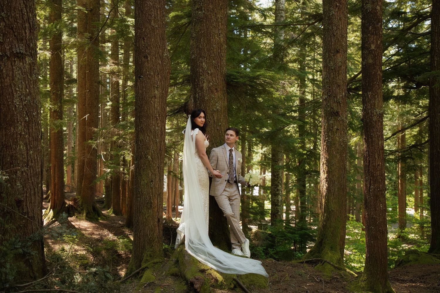 Bride and groom standing among towering evergreen trees during an intimate forest elopement in Washington State
