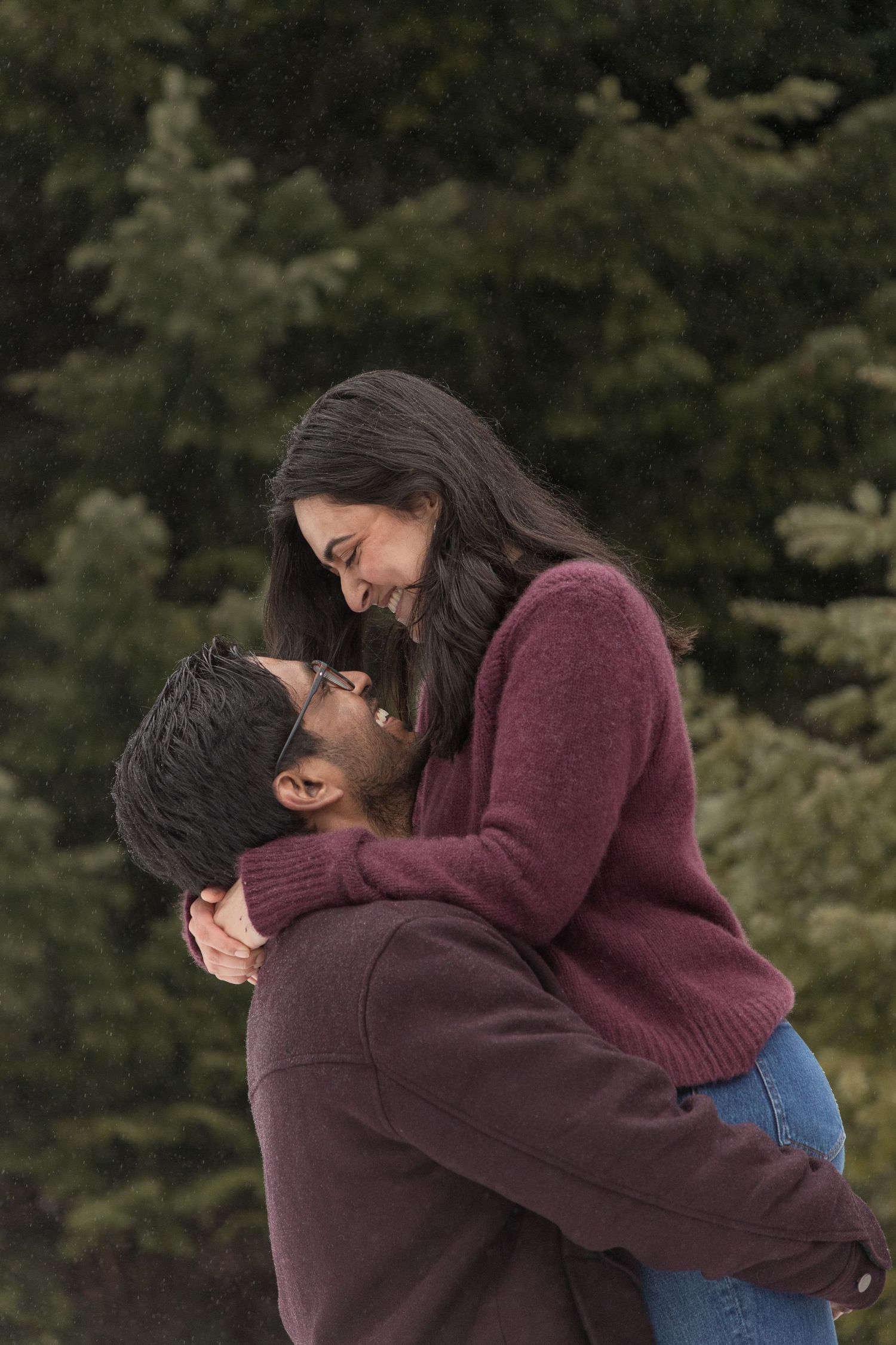 Couple embracing in an evergreen forest during a romantic winter photoshoot in Washington