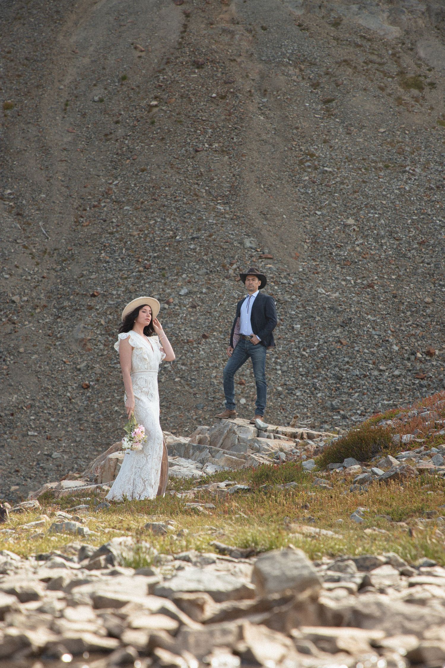 Bride approaching the groom on a rocky alpine slope during their Mount Rainier elopement