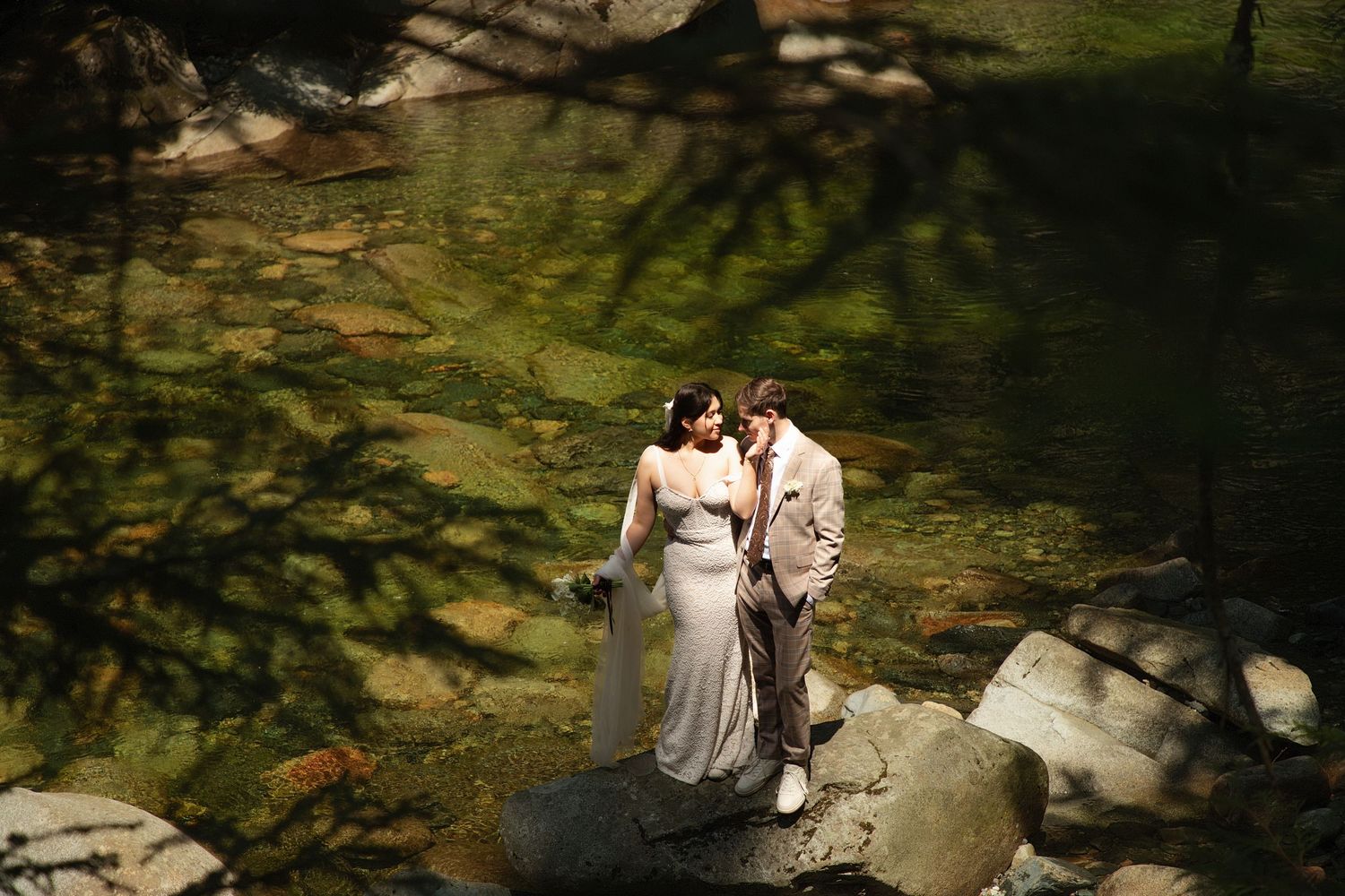 Bride and groom standing on riverside rocks during an intimate Washington forest elopement photoshoot