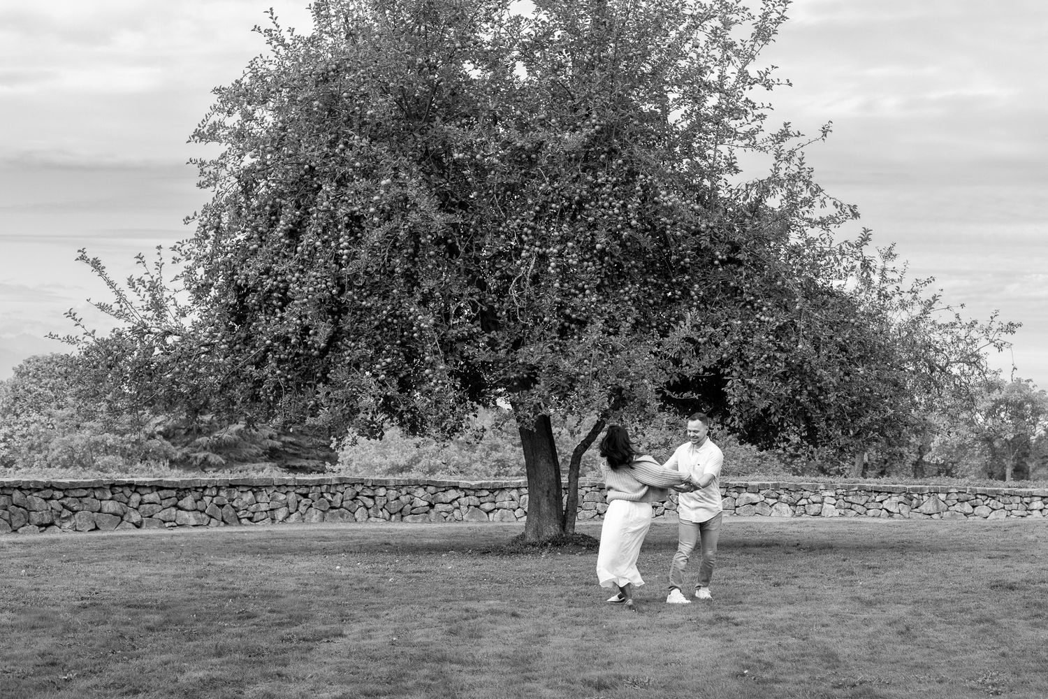 Seattle engagement photographer capturing a couple during an outdoor Discovery Park engagement photoshoot in an open field with trees