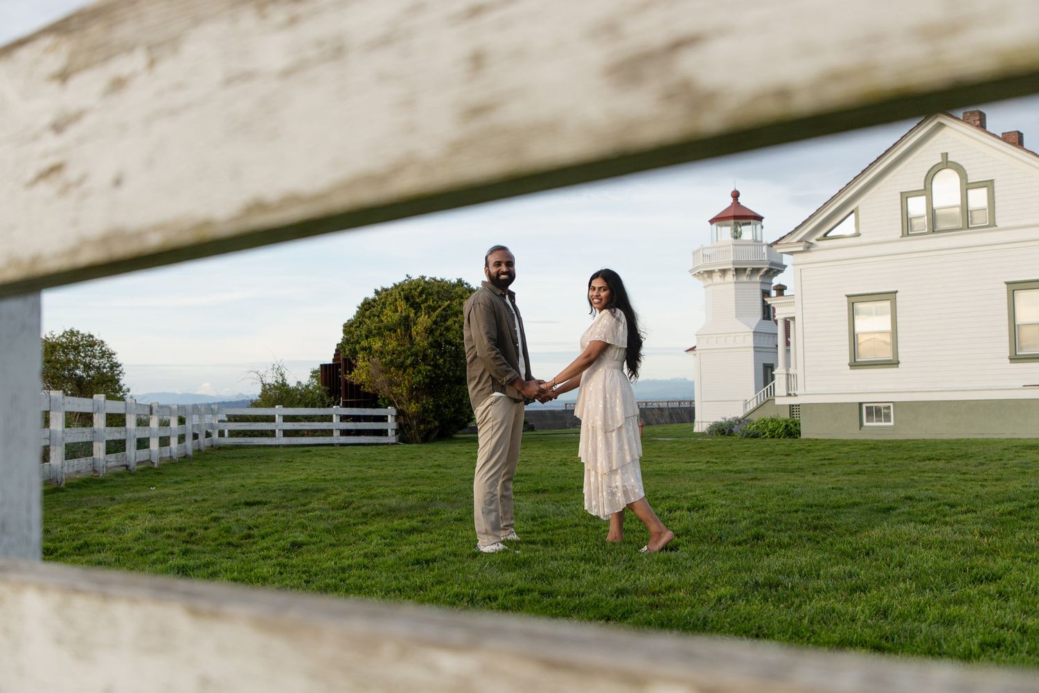 Engaged couple holding hands near the historic lighthouse at Mukilteo Lighthouse Park