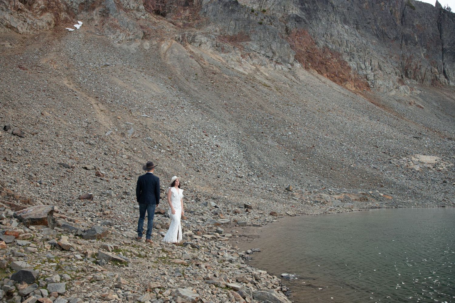 Newlyweds walking along the rocky shore of an alpine lake during their Mount Rainier elopement