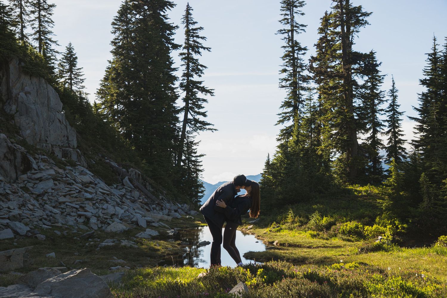 Newly engaged couple kissing beside an alpine pond in Mount Rainier National Park