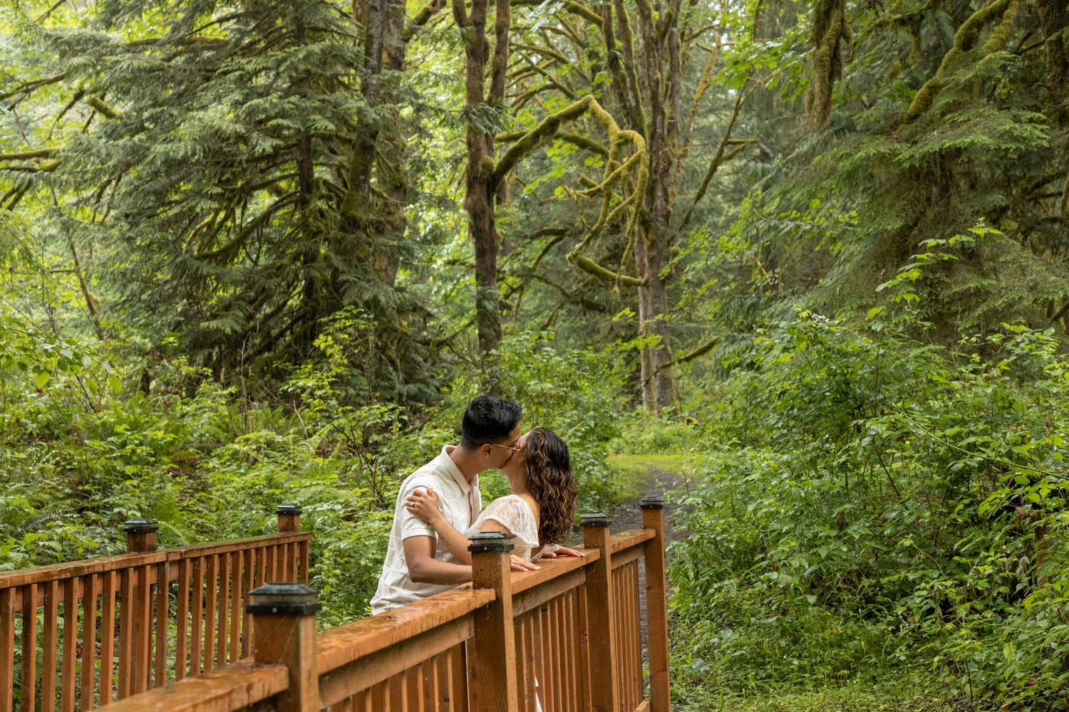 Couple kissing on a wooden bridge during a Snoqualmie Falls surprise proposal photoshoot