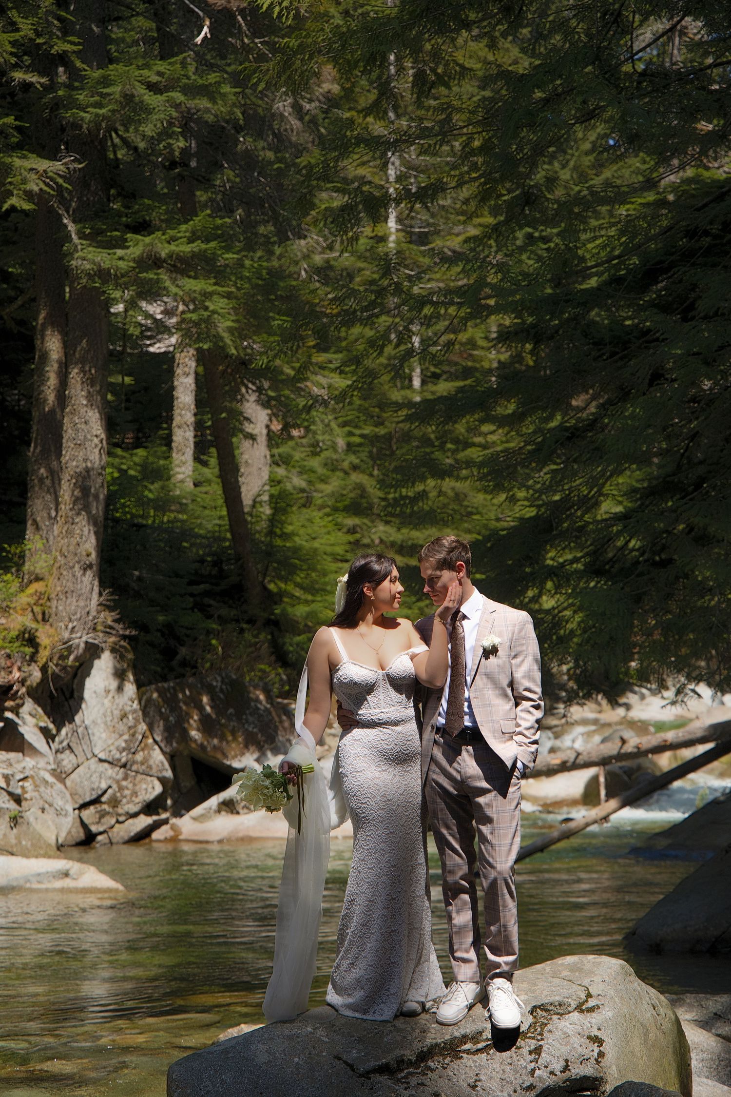 Bride and groom standing beside a mountain river during a Washington forest elopement photoshoot