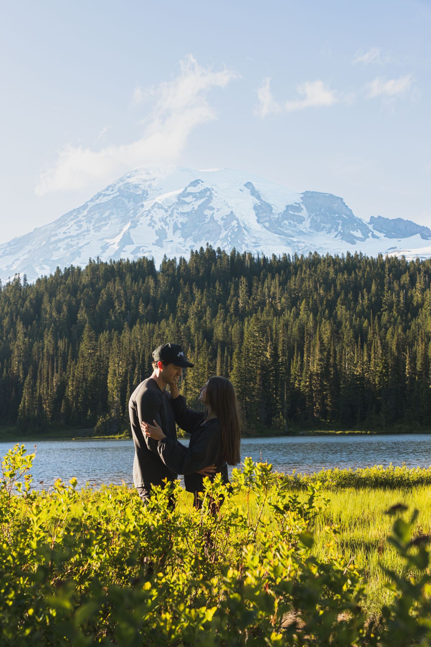 Couple embracing by Reflection Lake with Mount Rainier in the background during a surprise proposal session